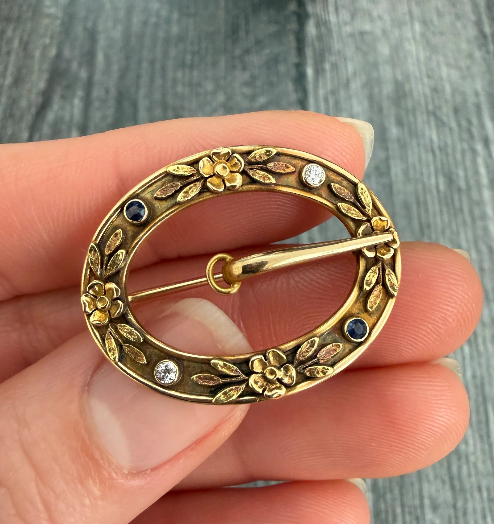 Art Nouveau Diamond and 14K Gold Floral Motif Buckle Pin: Metal: 14K Yellow Gold Weight: 4.4 gramsDiamonds: Approximately 0.14 caratsSapphires: Approximately 0.10 caratsMeasurements: 1 inch long by 1.25 inches wideMarkings: "14K" and Maker's marksCondition: 