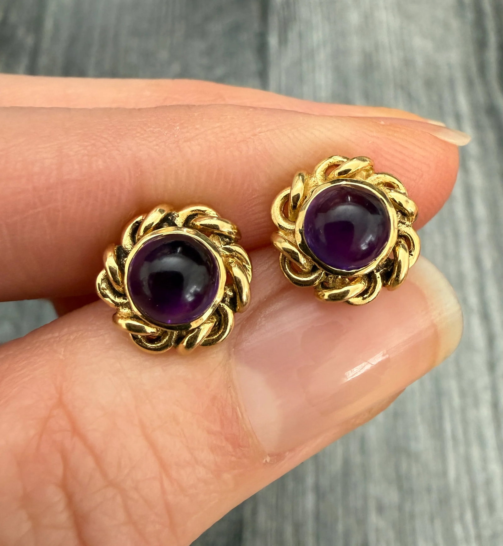 Cabochon Amethyst and Swirled Border Stud Earrings In 14K Gold: Metal: 14K Yellow Gold Weight: 3.4 gramsMeasurements: 0.45 inches diameterMarkings: None Condition: In very good condition with some minor surface wear.Follow us on Instagram @alphaomegajewelry for th