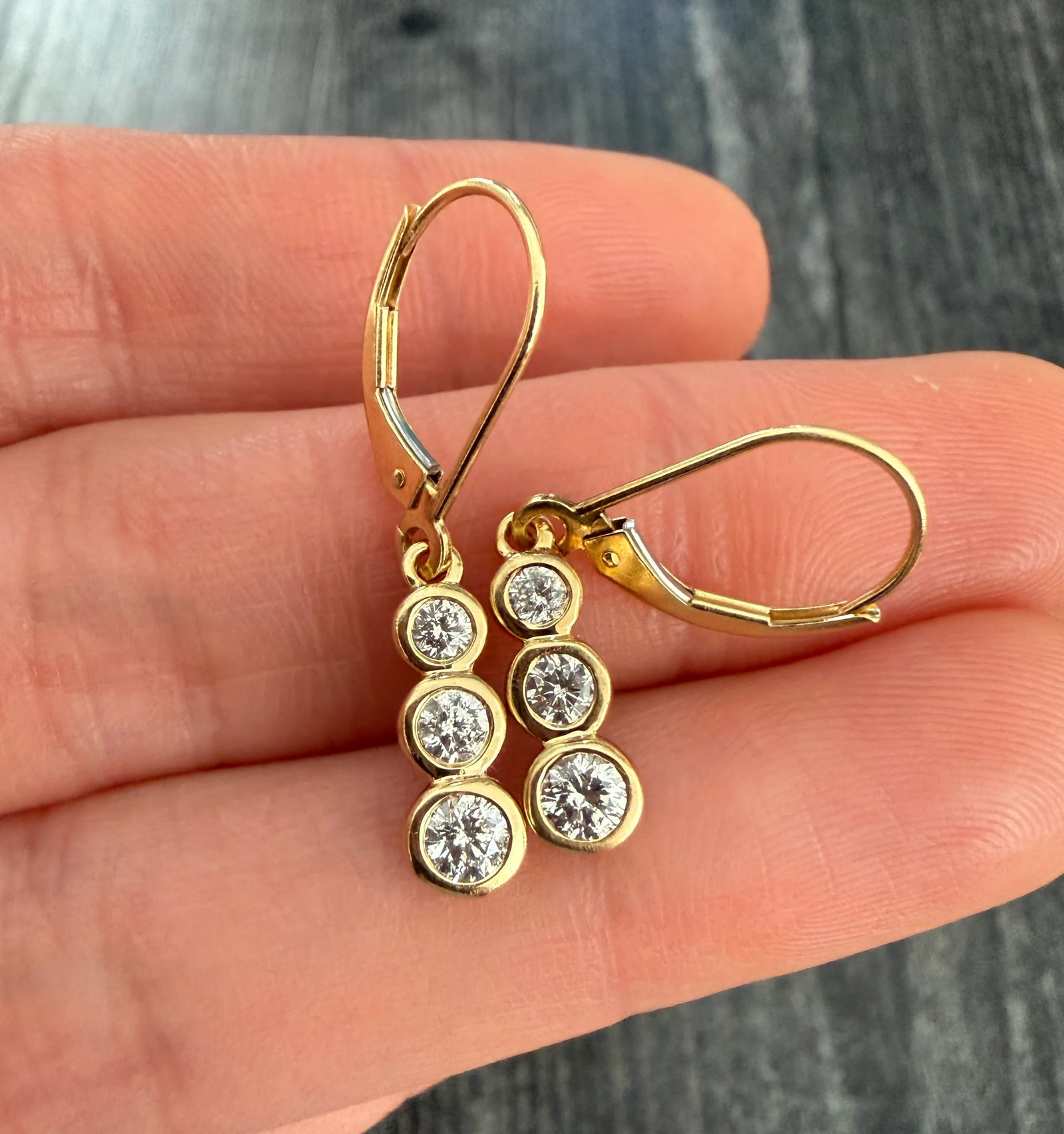Bezel Set Triple Diamond Dangle Earrings in 14K Gold: Metal: 14K Yellow Gold Weight: 2.6 gramsDiamonds: Approximately 0.90 caratsMeasurements: 1.2 inches longMarkings: "BH 14K"Condition: In very good condition with some minor surface wear consistent with