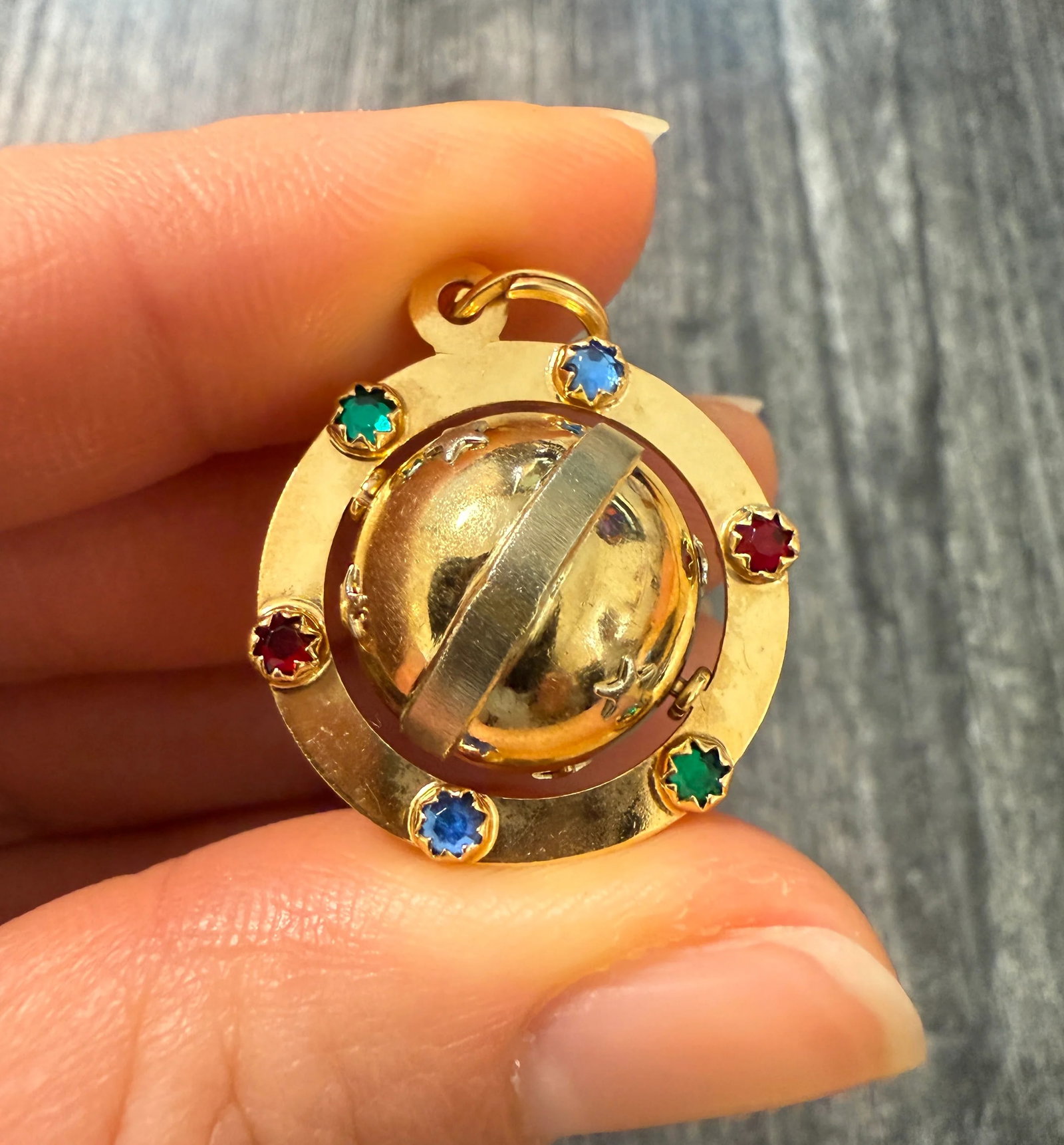 Vintage 18K Gold Spinning Saturn and Stars Charm: A magical spinning Saturn charm that is both rare and collectible. The piece is set with multicolored stones around the ring with star accents on the orb. Stamped "750" for 18K gold purity.Metal: 18K 