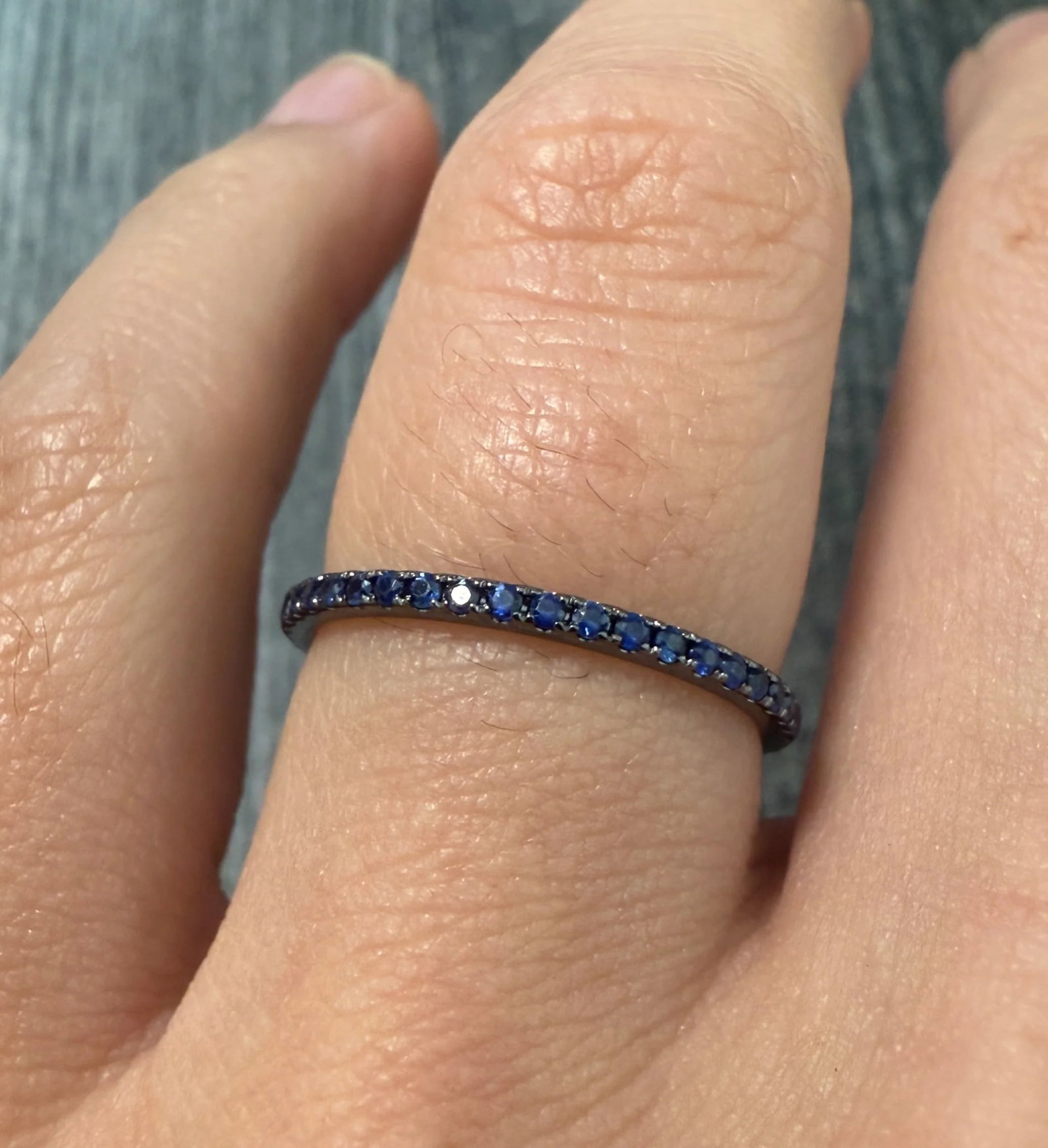 Blue Sapphire and 18K Black Gold Eternity Band, Size 6.5: Metal: 18K Black Gold (rhodium plated)Weight: 1.3 gramsSapphires: Approximately 0.40 caratsRing Size: 6.5 Wide: 1.4 mm widesMarkings: "18K 750 Au 15-1"Condition: In very good condition with some minor