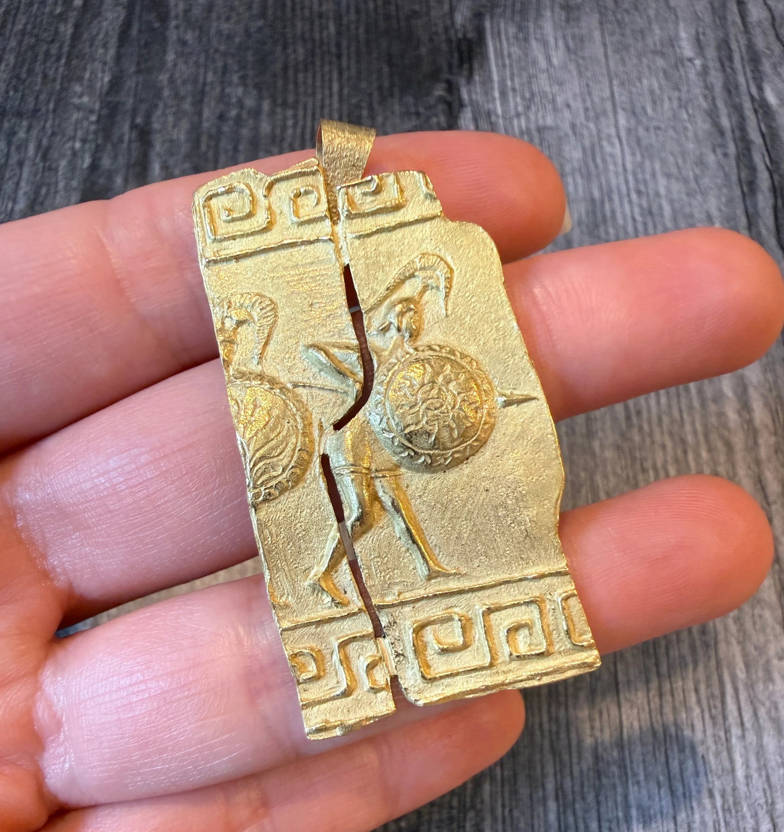Split Relief Ancient Greek Warrior Pendant in 18K Gold Pendant (I): Metal: 18K Yellow Gold Weight: 15.3 grams Measurements: 2 inches long by 1 inch wide Markings: "E.37 Greece 750" Condition: In very good condition with some minor surface wear.