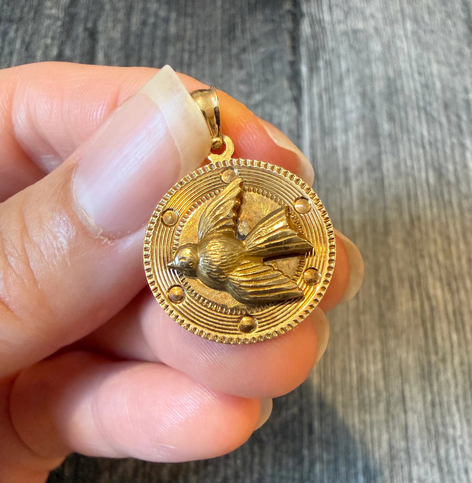 Vintage Engine Turned Dove of Peace Charm in 14K Gold: Metal: 14K Yellow GoldWeight: 3.1 gramsMeasurements: 0.75 inches diameter Markings: "14K"Condition: In good condition with an old repair behind the bird as well as some minor surface wear throughout