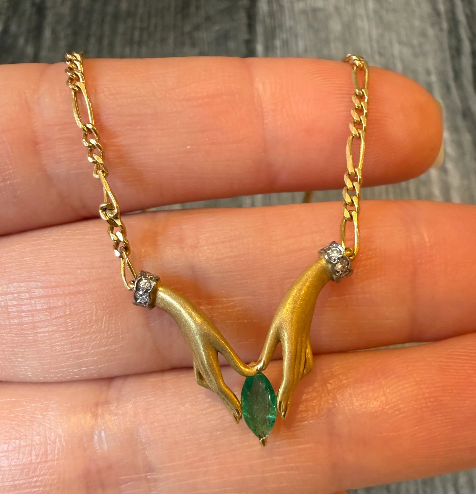 Two Hands Holding an Emerald Necklace in 18K Gold with Diamond Cuffs (I): Metal: 18K Yellow Gold Weight: 8.3 gramsEmerald: Approximately 0.35 caratsDiamonds: Approximately 0.06 caratsChain Measurements: 16.5 inches long by 2 mm wideMarkings: "ITALY 750"Condition: In very go