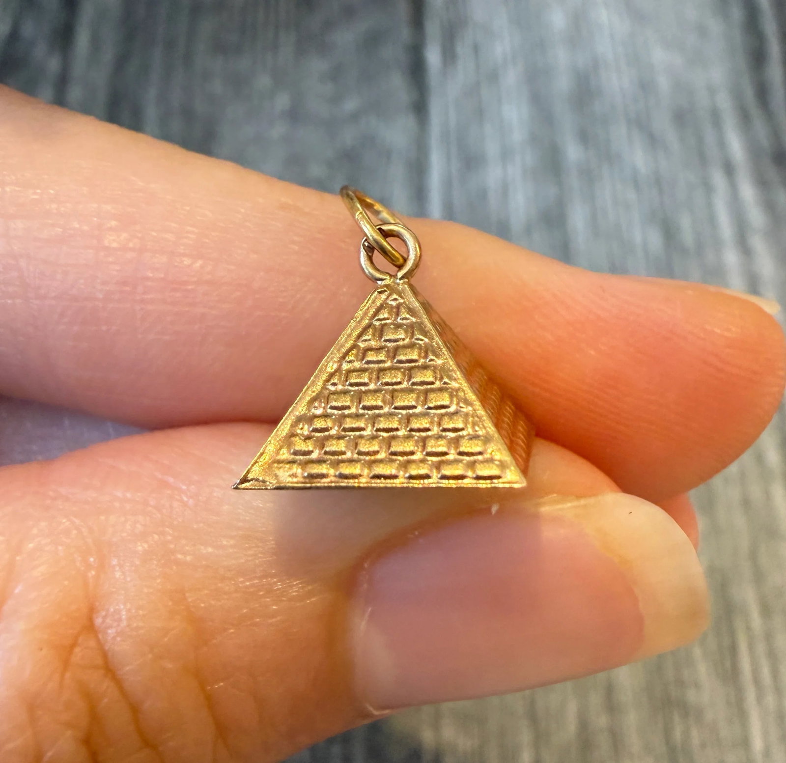 Egyptian Pyramid Charm in 18K Gold: Metal: 18K Yellow Gold Weight: 0.7 gramsMeasurements: 0.7 inches by 0.7 inches wideMarkings: Egyptian hallmarksCondition: In good condition with some minor dings on the bottom of the charm and some su