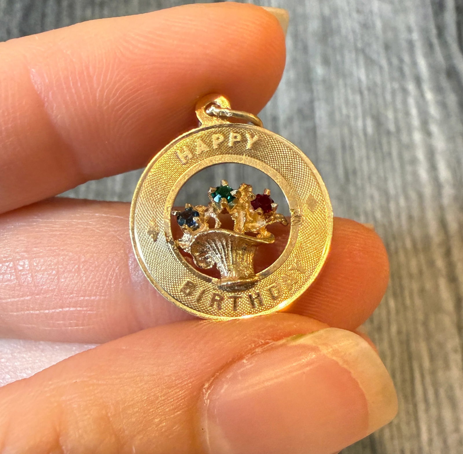 Happy Birthday Flower Basket Charm in 14K Gold: Metal: 14K Yellow Gold Weight: 1.4 gramsMeasurements: 0.75 inch diameterMarkings: "14K"Condition: In good condition with some minor surface wear consistent with age.
