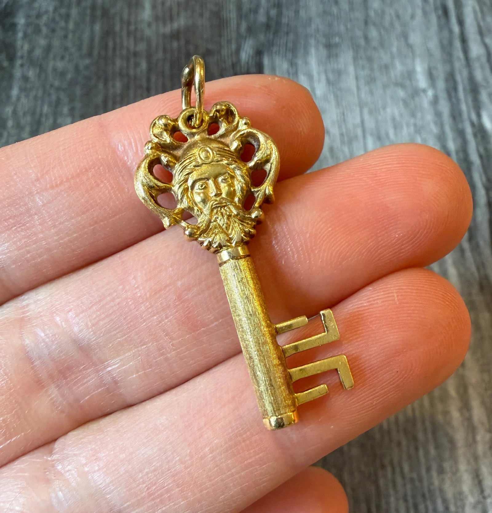 Vintage Green Man Skeleton Key Charm in 18K Gold: Metal: 18K Yellow Gold Weight: 5.1 gramsMeasurements: 1.4 inches long by 0.65 inches wide Markings: "18K"Condition: In very good condition with some minor surface wear