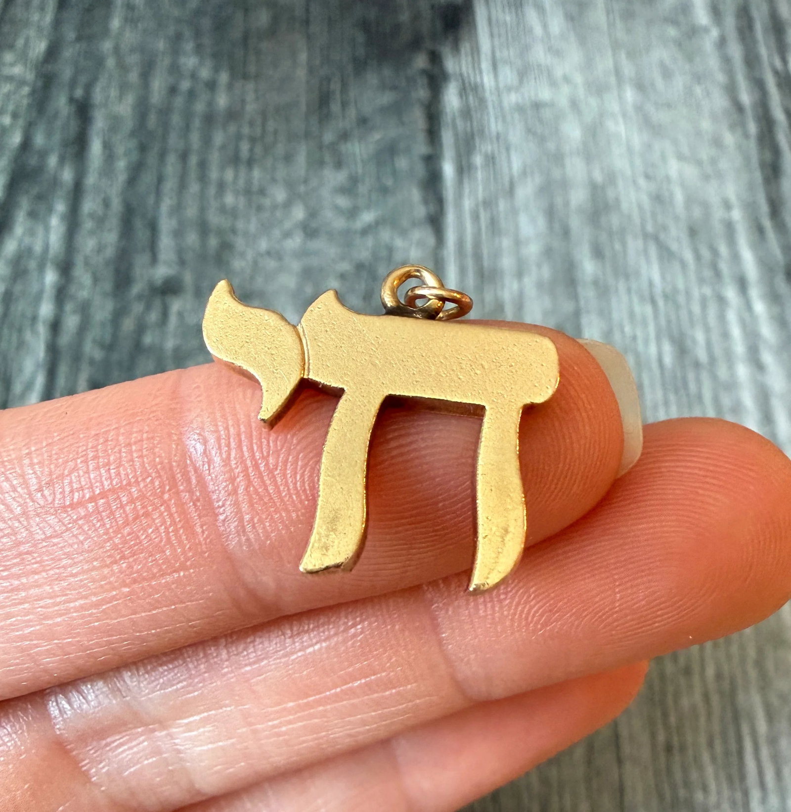 Chai Charm in 14K Gold: Metal: 14K Yellow Gold Weight: 3.5 gramsMeasurements: 0.7 inches long by 0.8 inches wideMarkings: "14K"Condition: In good condition with some minor surface wear Follow us on Instagram @alphaomegajewel
