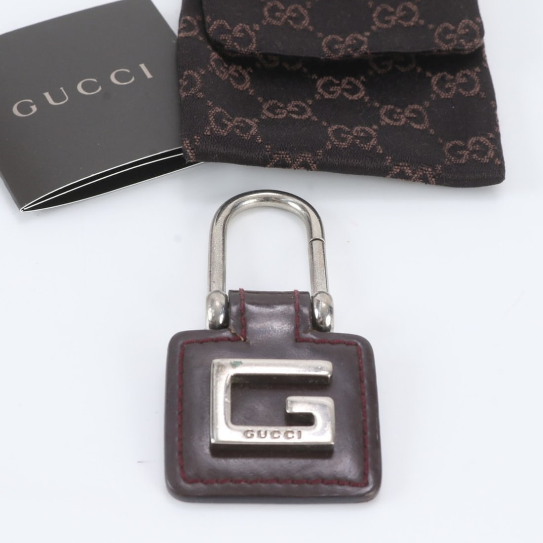 Gucci G-logo bag charm key ring strap leather holder for men and women: --- Catalog ---Category: SizeSize (HxWxD): 7.5cm x 3.8cm / 2.95'' x 1.49''Category: DesignType: KeyringColor: Brown, SilverGender: Men,WomenMaterial: LeatherCategory: GeneralBrand: GucciCountry of Ori