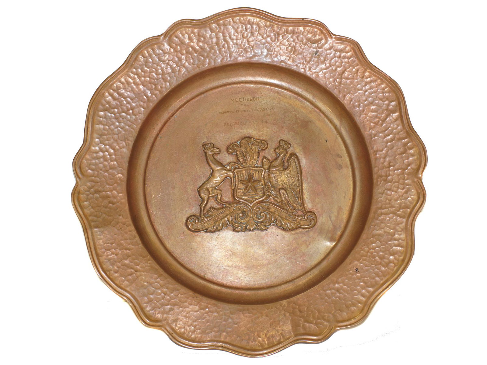 A COMMEMORATIVE PLATE BY SHCERING CORP, CHILE, 1953: A copper hand-hammered commemorative plate made for the Schering Corporation with the names of its executives, featuring the Chilean coat-of-arms in the center, dated November 1953. Dimensions: D: 14 