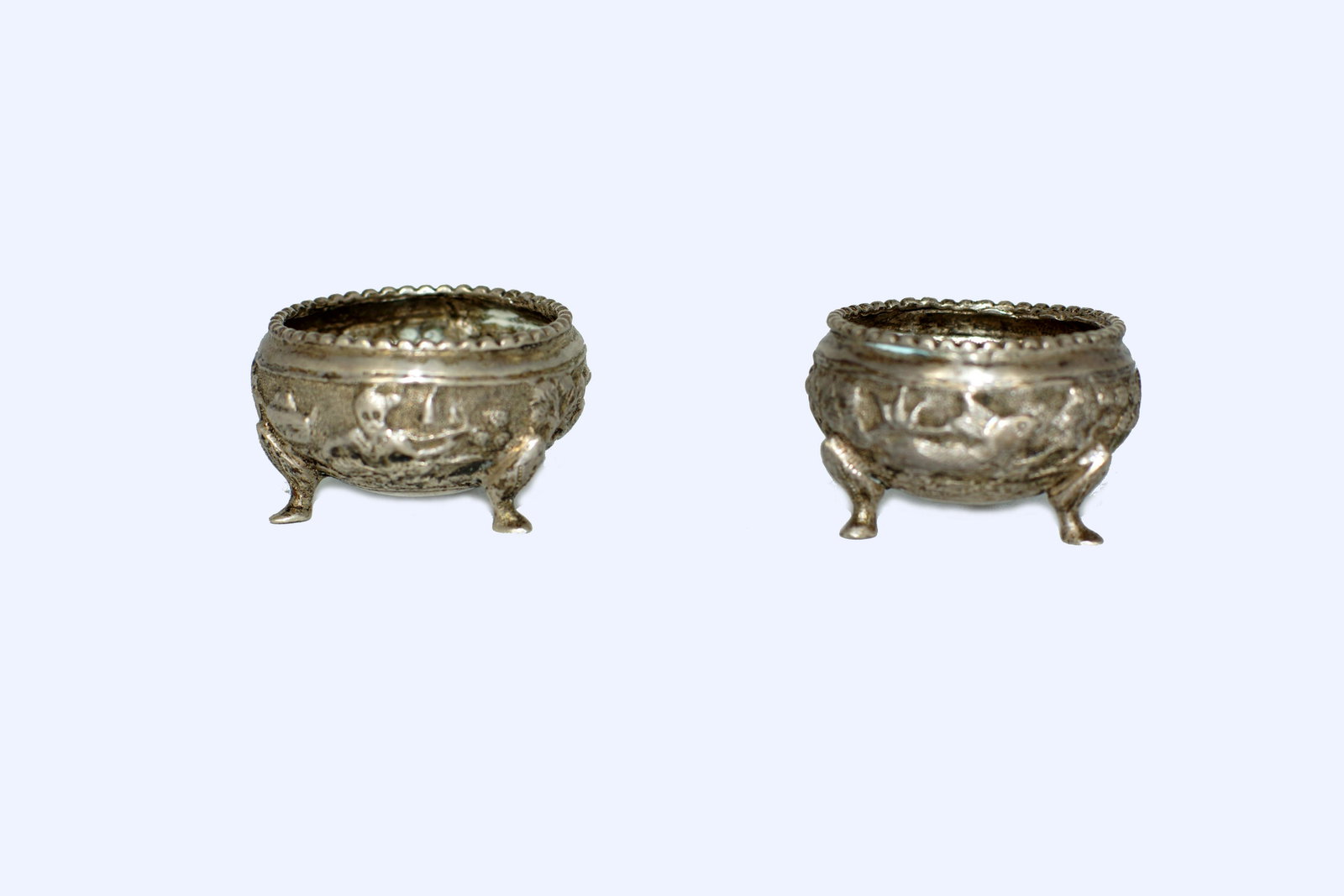 AN ANTIQUE CHINESE EXPORT SILVER SALT CELLARS: A rare Chinese export silver salt cellars with a relief design depicting classic Asian landscape with a house, tiger and old Chinese man. Unmarked. Weight 2.08 oz., 59 gr. Circa late 19th century. Dim