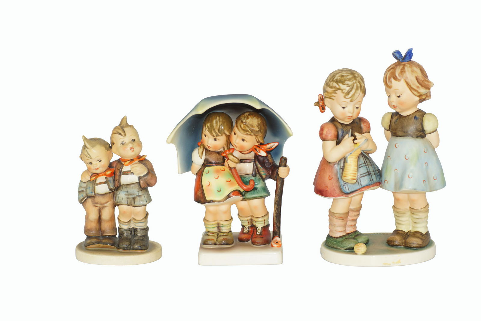 A GROUP OF VINTAGE GOEBEL HUMMEL FIGURINES: A group of three Goebel Hummel figurines, 256 knitting lesson, 71 stormy weather, 123 Max and Moritz. Dimensions: Smallest: H 5.25 in. Largest: H 7.5 in.