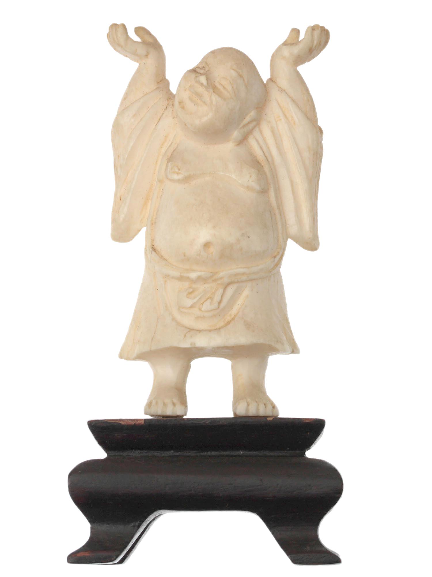 A JAPANESE CARVED NETSUKE OKIMONO OF HOTEI 19TH C: Hotei, one of the seven lucky gods of Japan. It is the epitome of abundance and good health. Depicted with a laughing face and a big belly. On this Meiji period figurine, Hotei stands on a miniature w