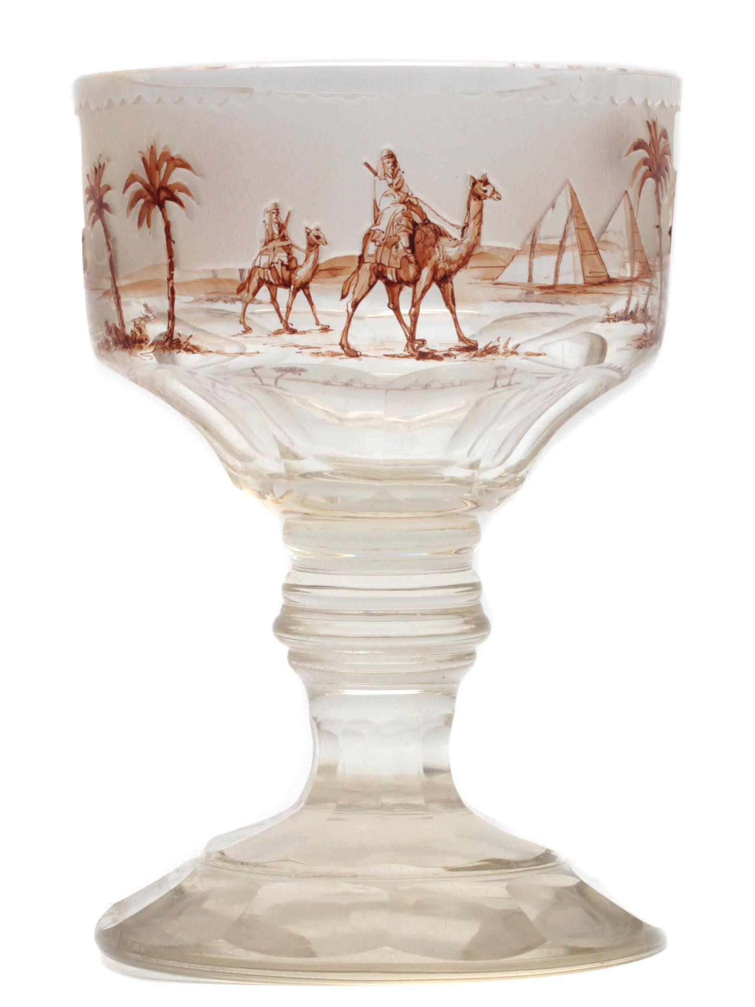AN ANTIQUE GLASS GOBLET WITH MIDDLE EASTERN SCENE: A 19th century glass goblet. A frosted glass upper with an embossed hand-painted scene depicting travelers riding camels among pyramids and palms. Dimensions: H: 8 in., (20 cm.)