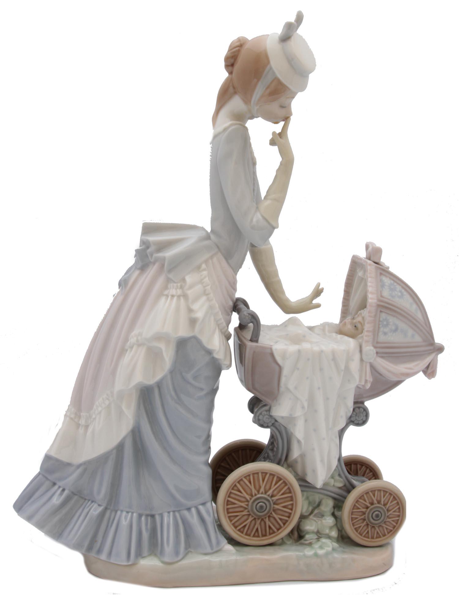 A VINTAGE LLADRO PORCELAIN FIGURINE: An adorable Lladro glazed porcelain figurine depicting a young mother in a Victorian dress walking with her baby in a stroller. Stamped on the base with "LLADRO /HAND MADE IN SPAIN". Dimensions: 13 x 