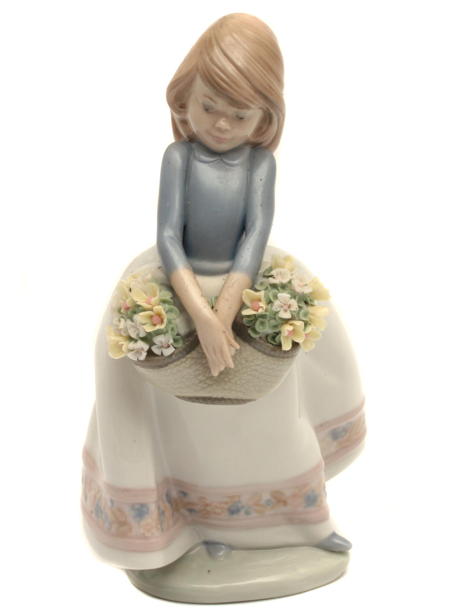 A VINTAGE SPANISH LLADRO DAISA PORCELAIN FIGURINE: An adorable porcelain figurine depicting a girl with a basket full of spring flowers. All the details are made very carefully, in particular, this is noticeable by the thinnest flower petals and by th