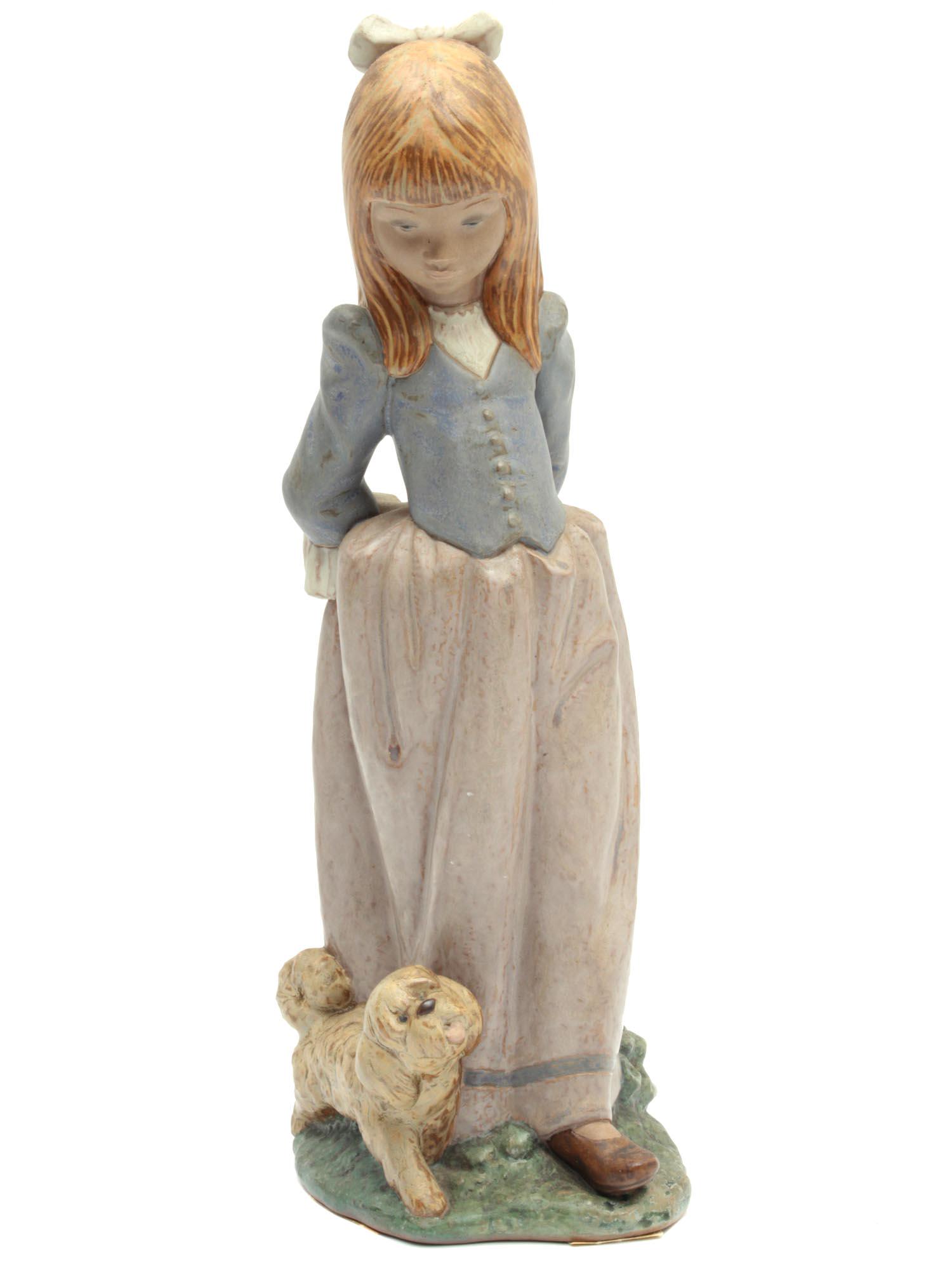 A VINTAGE SPANISH LLADRO DAISA PORCELAIN FIGURINE: An adorable porcelain figurine depicting a walking girl with a puppy. The girl's hair is decorated with a white ribbon, she is dressed in a lovely dress. On the base there is a date 1979 and blue manu