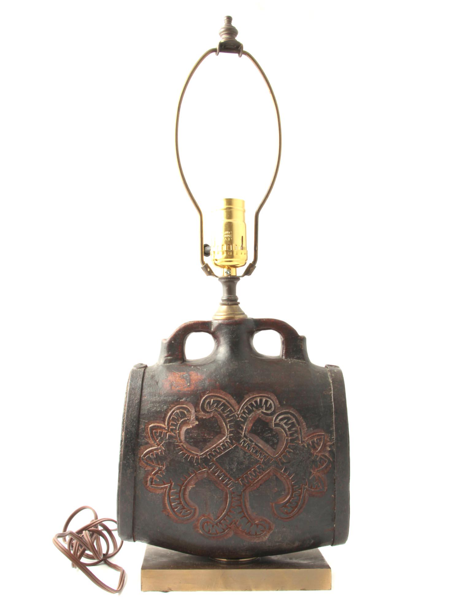 A VINTAGE CHINESE TABLE LAMP ON A WOODEN STAND: A lamp on a wooden stand in the shape of a flat drum. With a carved pattern on the front and side. Dimensions: H: 21 1/2 in., (54.6 x cm.)