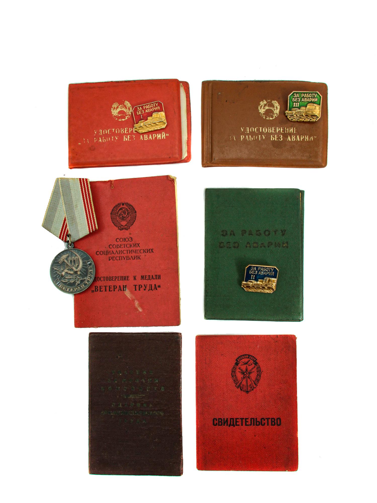 A GROUP OF DOCUMENTED SOVIET RUSSIAN MEDAL AND BADGES: This set of Soviet medals and badges are accompanied by their official documents in the name of Podolyak Vasily Stepanovich. The set also contains a certificate of completion of advanced training and