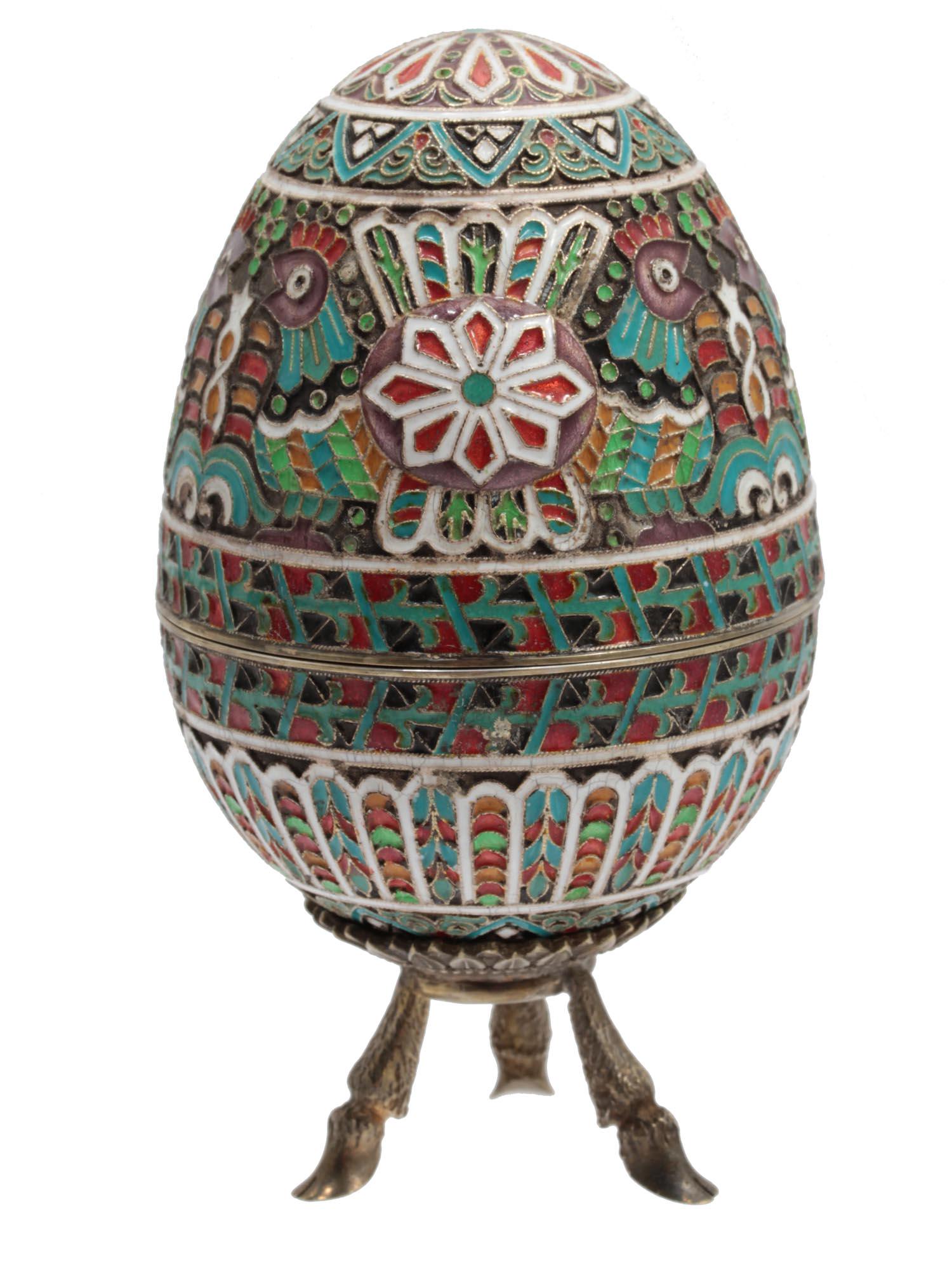 A LARGE RUSSIAN GILT-SILVER AND ENAMEL EASTER EGG: A large Russian gilt-silver enameled egg ovoid in two halves on a three-legged stand. The base interior is the gilt covered, the exterior is blue, green, and red geometrical and floral ornament decora