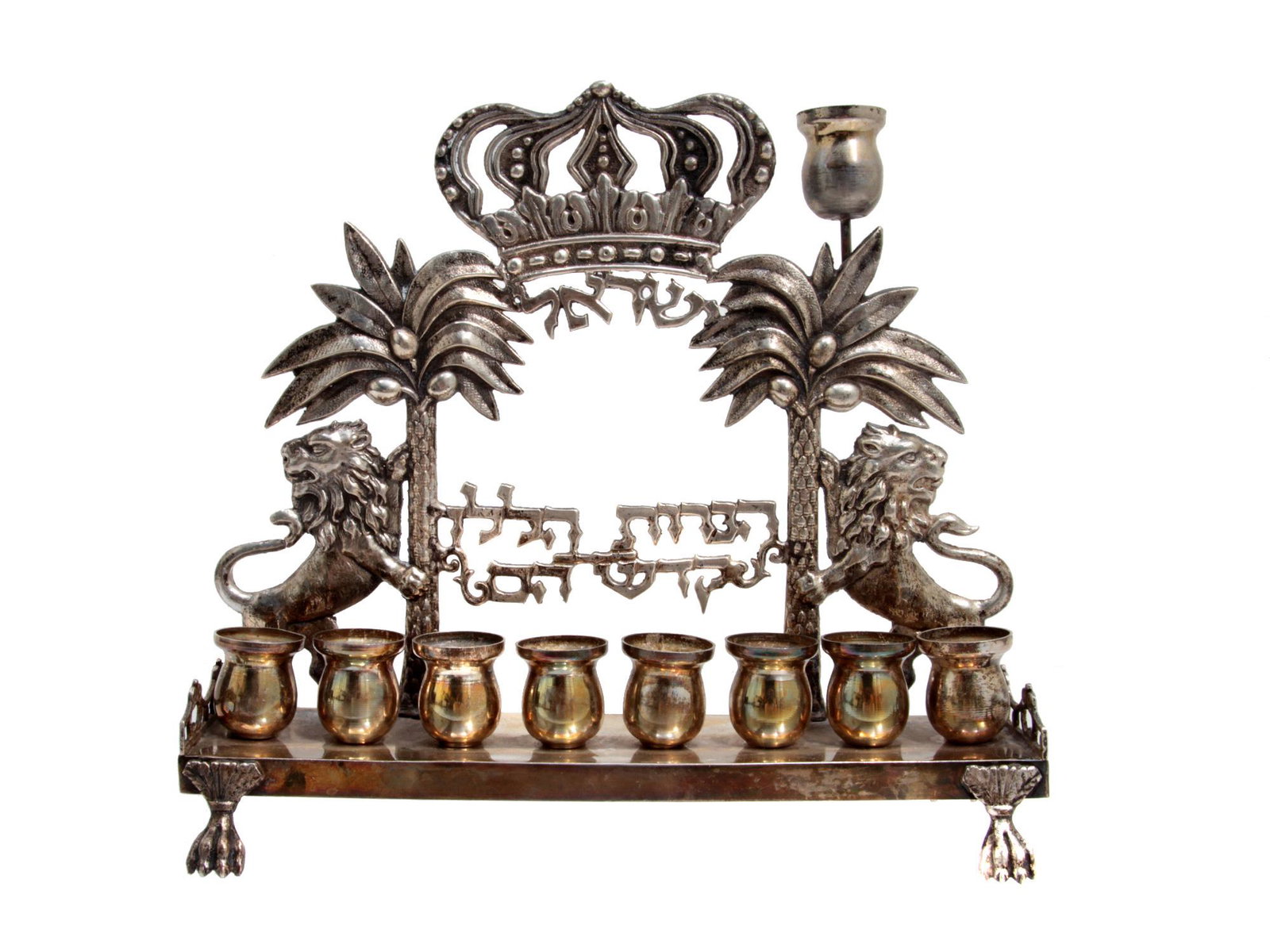 A SILVER ANTIQUE HANUKKAH MENORAH LAMP, 19TH C.: An antique Passover lamp with embossed decorations. Of the characteristic design, elements are two lions leaning on the trunks of palm trees. At the top, there is a large pierced Torah crown. To the r