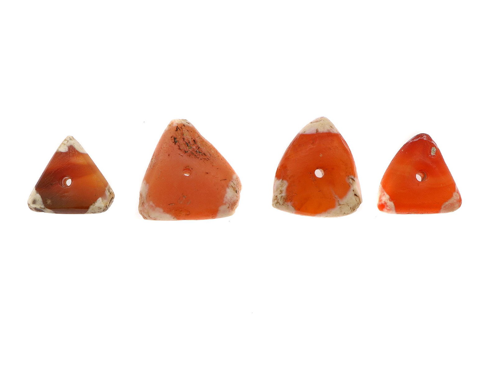 WEST ASIA ETCHED CARNELIAN BEADS, 2500 B.C.: Four triangular etched carnelian beads. All four beads have their angles etched white. Dimensions: Smallest L: 3/8 in.,10 mm. Largest L: 1/2 in., 12 mm.