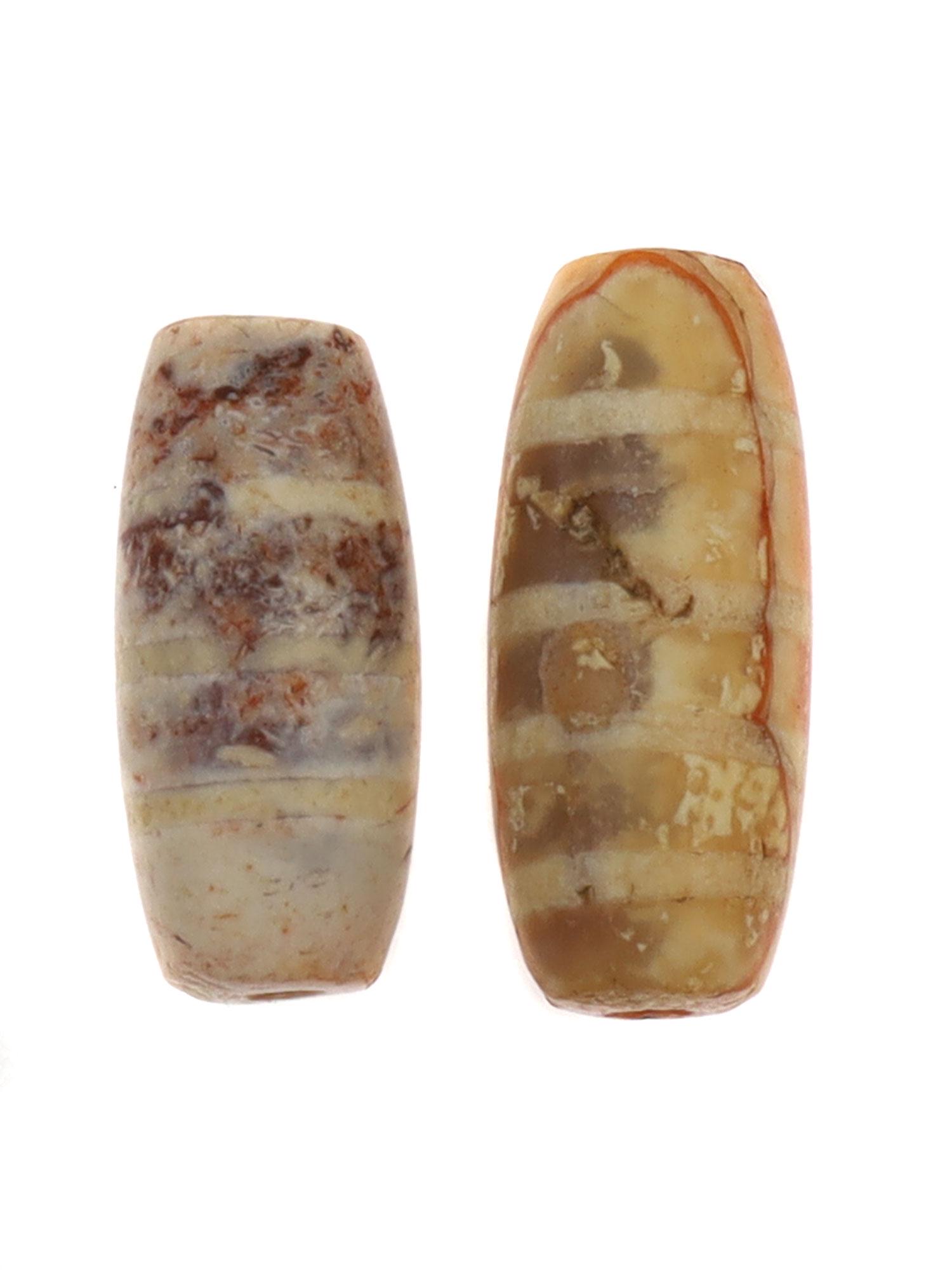 WEST ASIA ETCHED CARNELIAN BEADS, 2500 B.C.: The cornelian tubular beads clearly show their valuable age as they are covered in patina. The white etched lines create a striped pattern that is visible on the beads. Dimensions: Smallest L: 5/8 in,