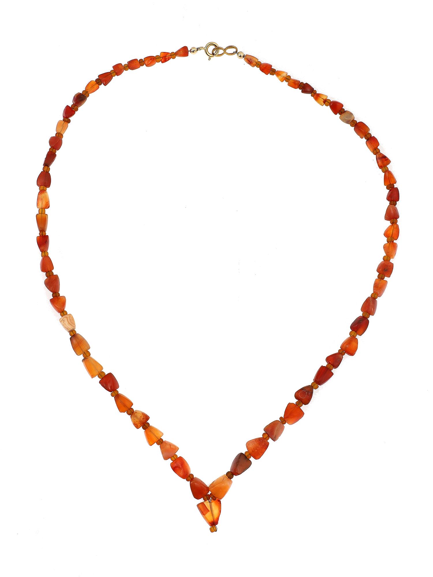 WEST ASIA CARNELIAN BEADS NECKLACE, 2500 BC: Composed of unique three-dimensional trapezoid beads, interspersed with glass bead spacers, strung with modern spring closure. Dimensions: 20 in.