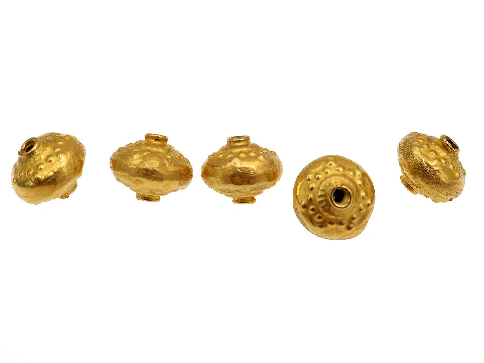 FIVE 18 KARAT GOLD BEADS: An 18 karat decorated hollow gold spacer.Weight: 0.0881 oz., 2.57 gr. Dimensions: 6mm.