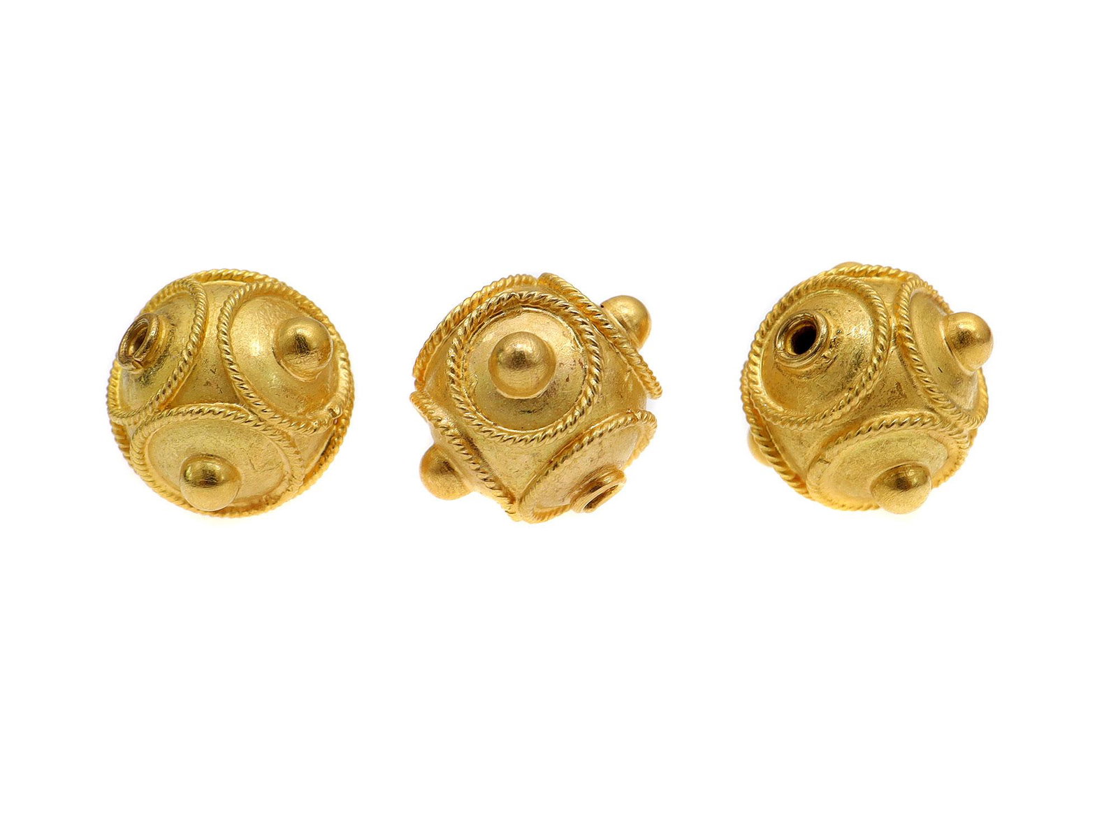 THREE 18 KARAT GOLD BEADS: An 18 karat decorated hollow gold spacer.Weight: 0.0807 oz., 2.29 gr. Dimensions: 8mm.