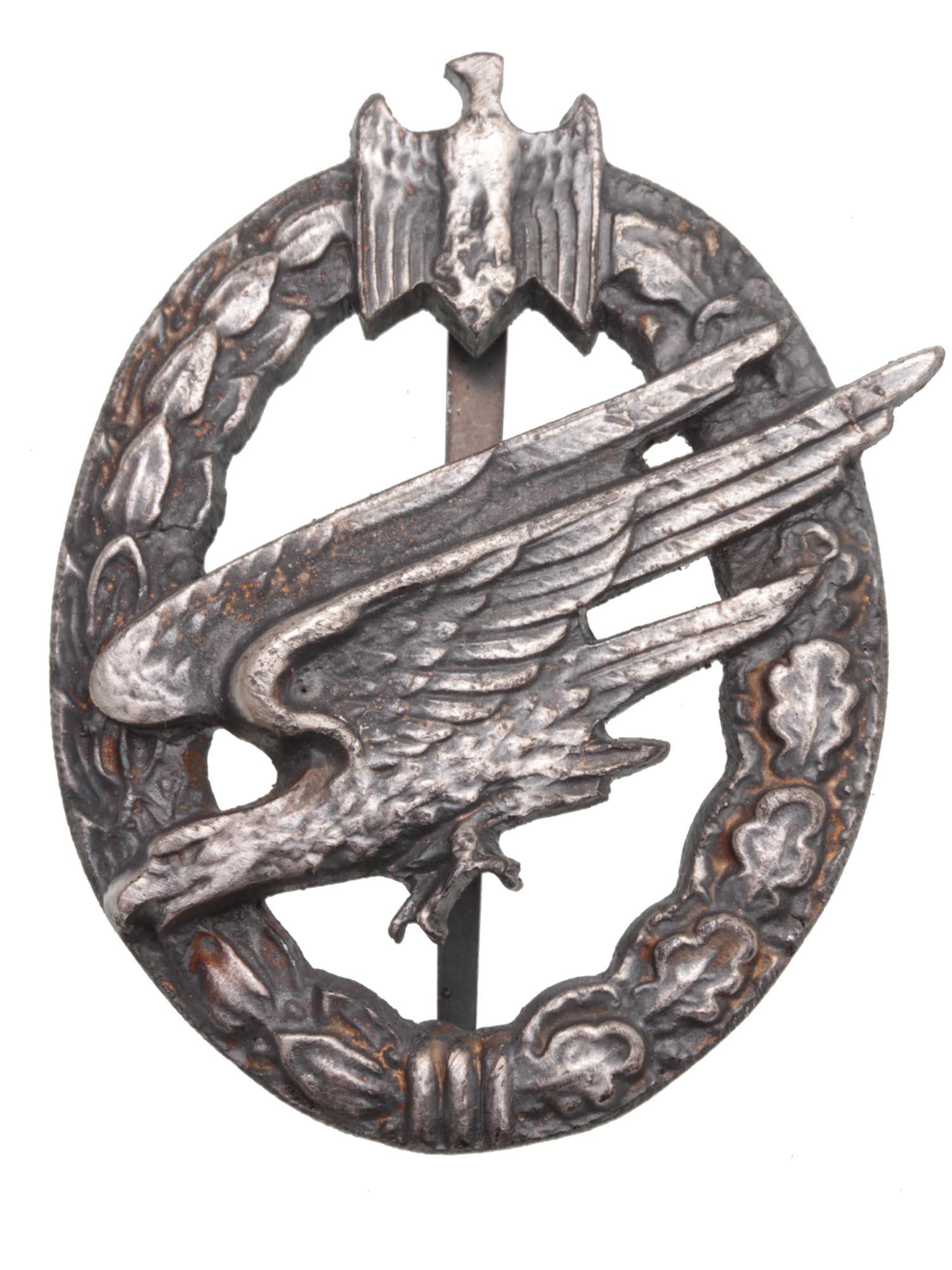 A WWII GERMAN ARMY PARATROOPERâ€™S BADGE: This is a WWII German Army Paratrooper Badge. The diving eagle is at the center of a metal-base laurel and oak leaves wreath. The Paratrooper Badges were introduced as a qualification awards for Parat