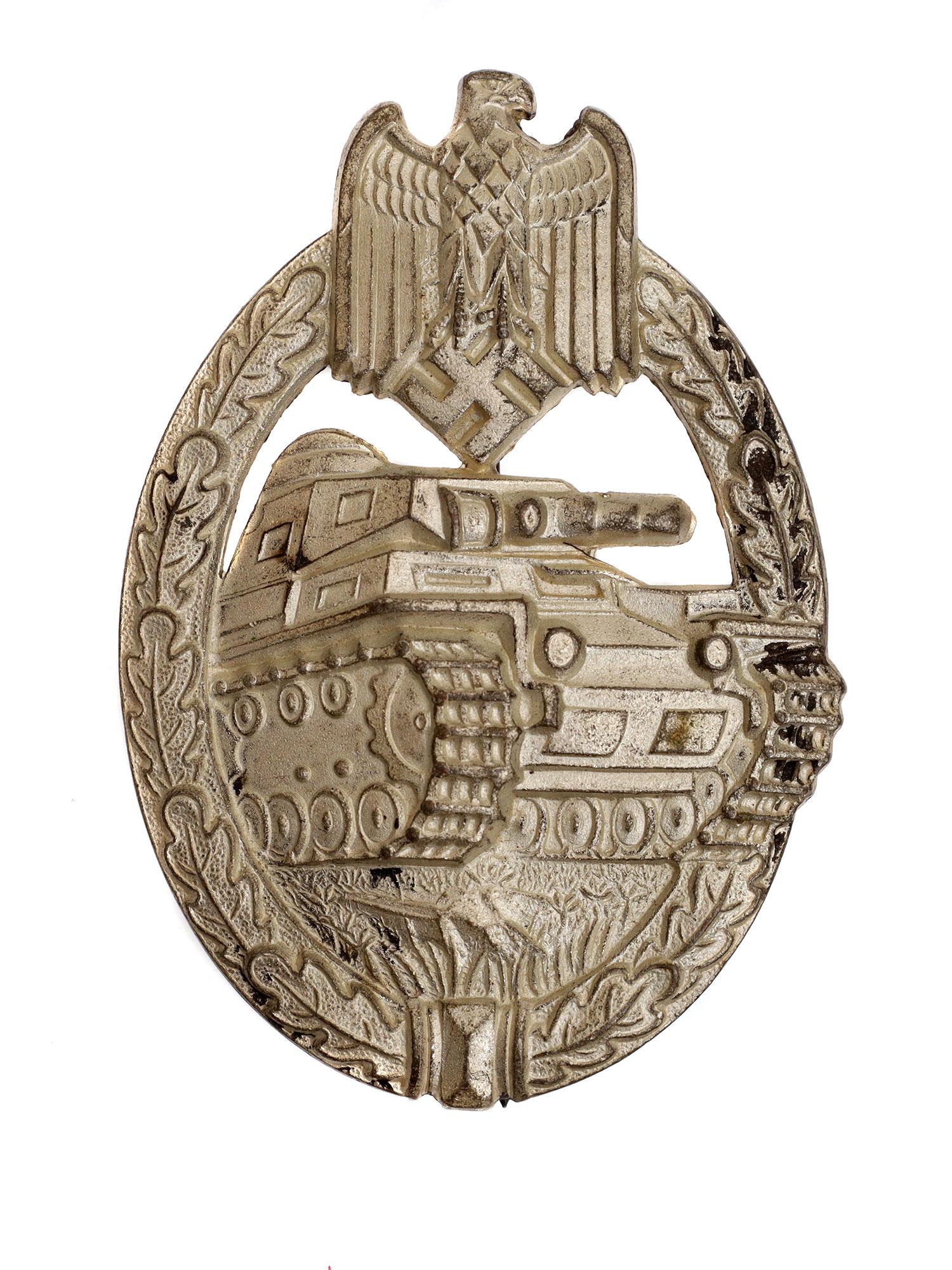 A VINTAGE NAZI GERMAN WWII PANZER BADGE: The badge has an oval shape and is a three-quarter front image of a Panzer IV tank, surrounded by an oak wreath and topped with a Wehrmacht eagle and a swastika. On the reverse, there is a pin fasteni