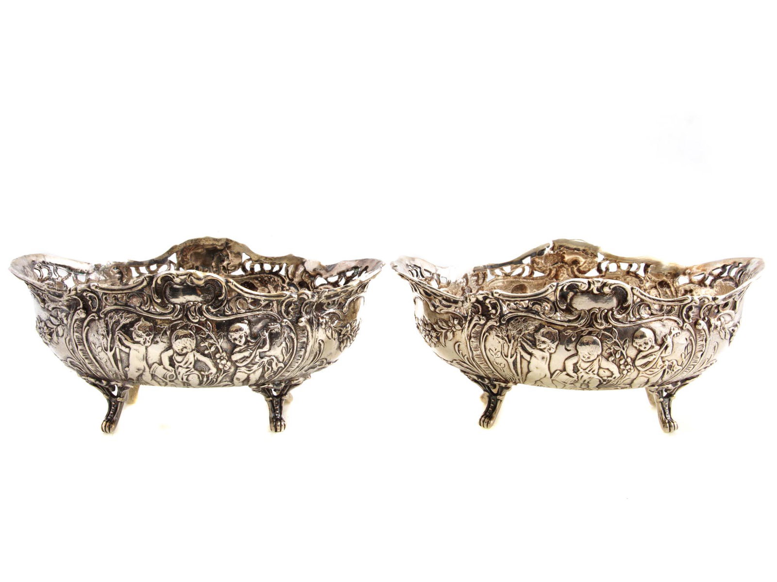 TWO ANTIQUE AMERICAN SILVER-PLATED CENTERPIECES: Two elegant centerpieces by the E. G. Webster and Sons. Made in the Rococo style, the edge is cut through, on the body, there are relief curls, flower garlands, and putti figurines. On four legs, made