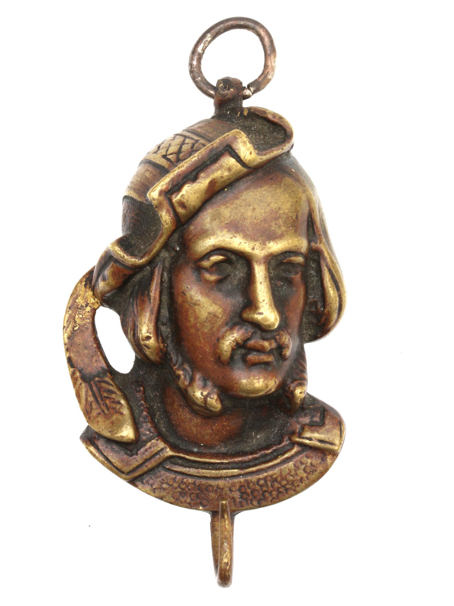 AN ANTIQUE VICTORIAN GILT COPPER PENDANT: An antique pendant in the form of a bust of a man in a Renaissance hat with a feather. The pendant is hollow inside; there is a hook at the bottom, probably for attaching an additional decoration. The