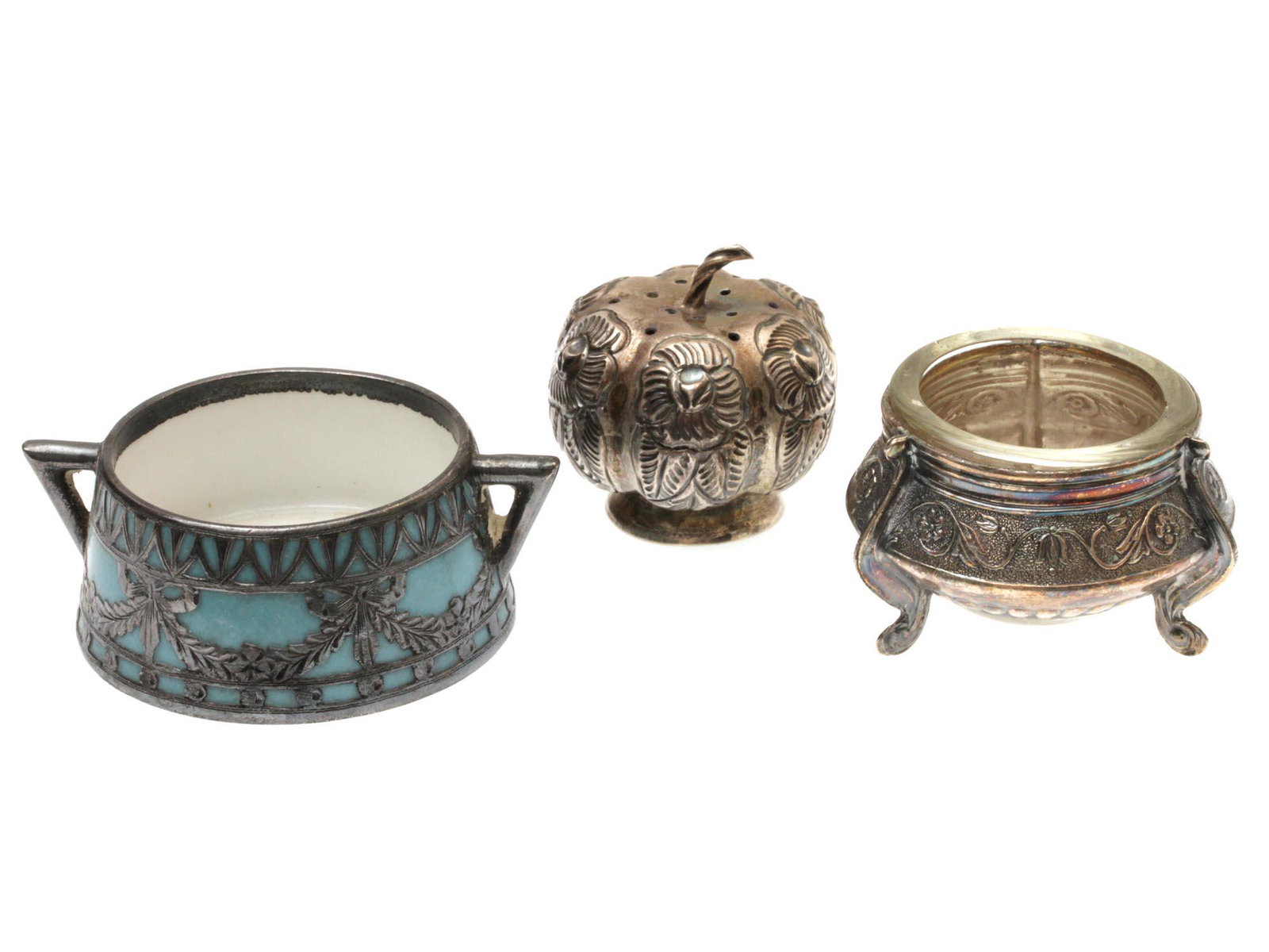THREE VINTAGE SILVER & SILVER PLATED SALT CELLARS: The lot includes:1. A silver pumpkin-shaped salt shaker, the surface of which is decorated with relief flowers. Marked on the base SILVER MEXICO.2. A vintage three-legged silver-plated salt cellar wit
