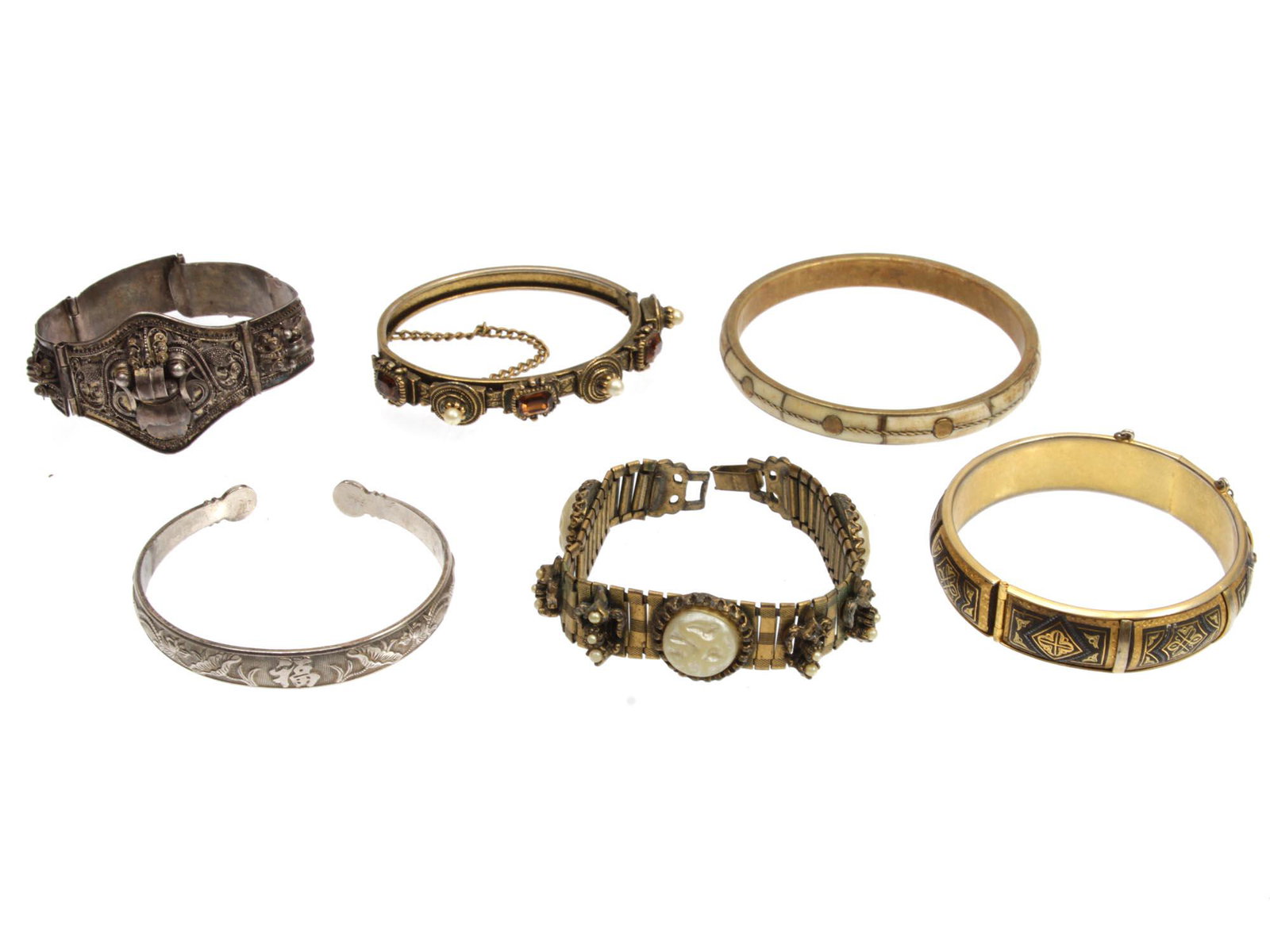 A LOT OF SIX VINTAGE BRACELETS SILVER & BRASS: This is a lot of custom assorted bracelets. Included: a gorgeous antique silver bracelet designed in five panels with the depiction of a demon in the central panel, possibly from Balinese origin. The 
