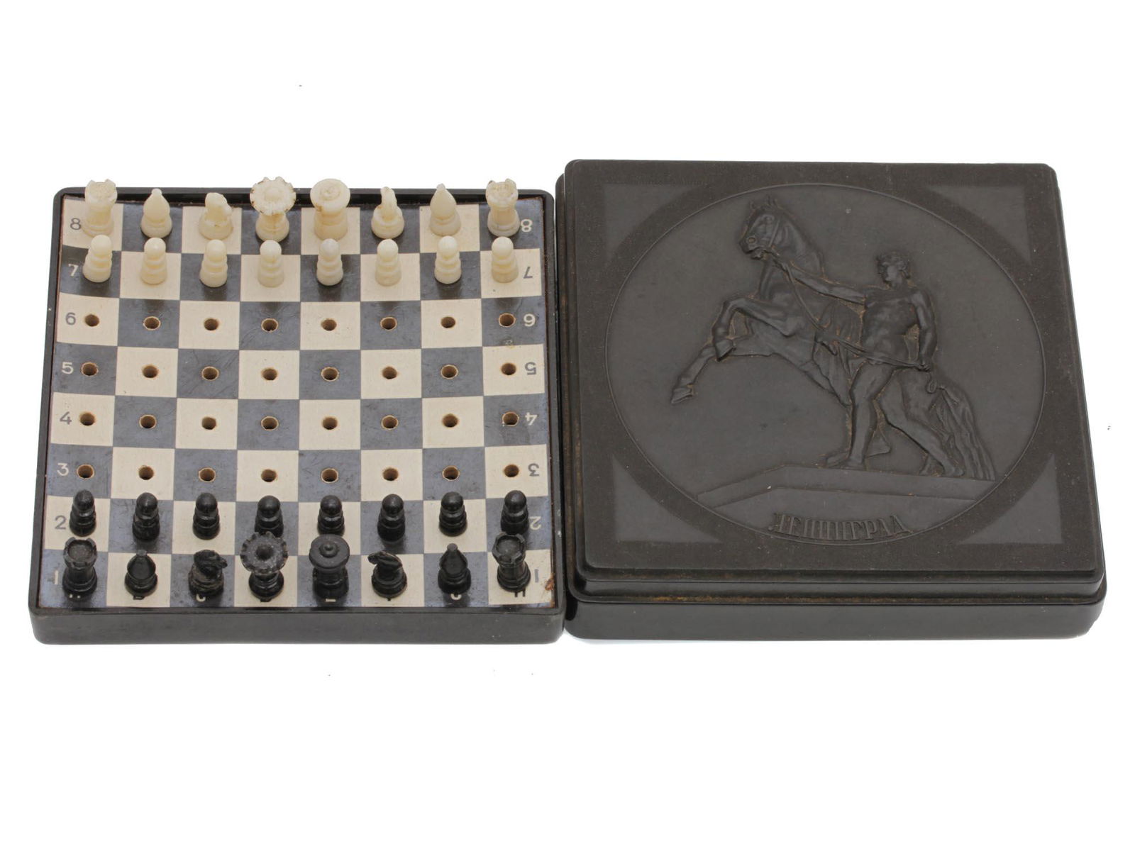 A RARE SOVIET LENINGRAD TRAVEL CHESS SET: This is a vintage Russian Leningrad travel chess set. The board is constructed of wood and the Chess pieces are made of plastic. It has a beautiful mate Black hard plastic case. Dimensions: 3 5/8 x 3
