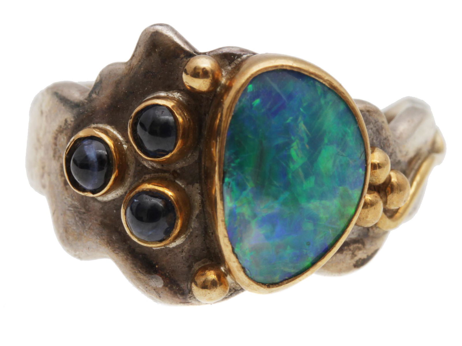 A VINTAGE STERLING SILVER RING WITH OPAL: A unique vintage sterling silver and partly gold plated ring. The ring is set with a large blue opal and three sapphire cabochons. Hand-engraved inside: Shano (?).Weight: 6.4 g. Dimensions: N/A