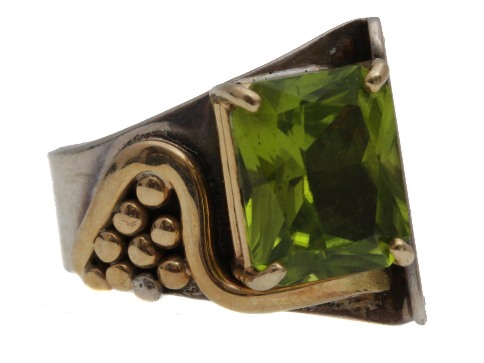 A SILVER AND GOLD PLATED RING WITH A GREEN STONE: A massive stunning sterling silver ring decorated with relief patterns in the shape of gilded rounds and curved line, with a unique design placing of faceted green stone. The ring is hallmarked inside