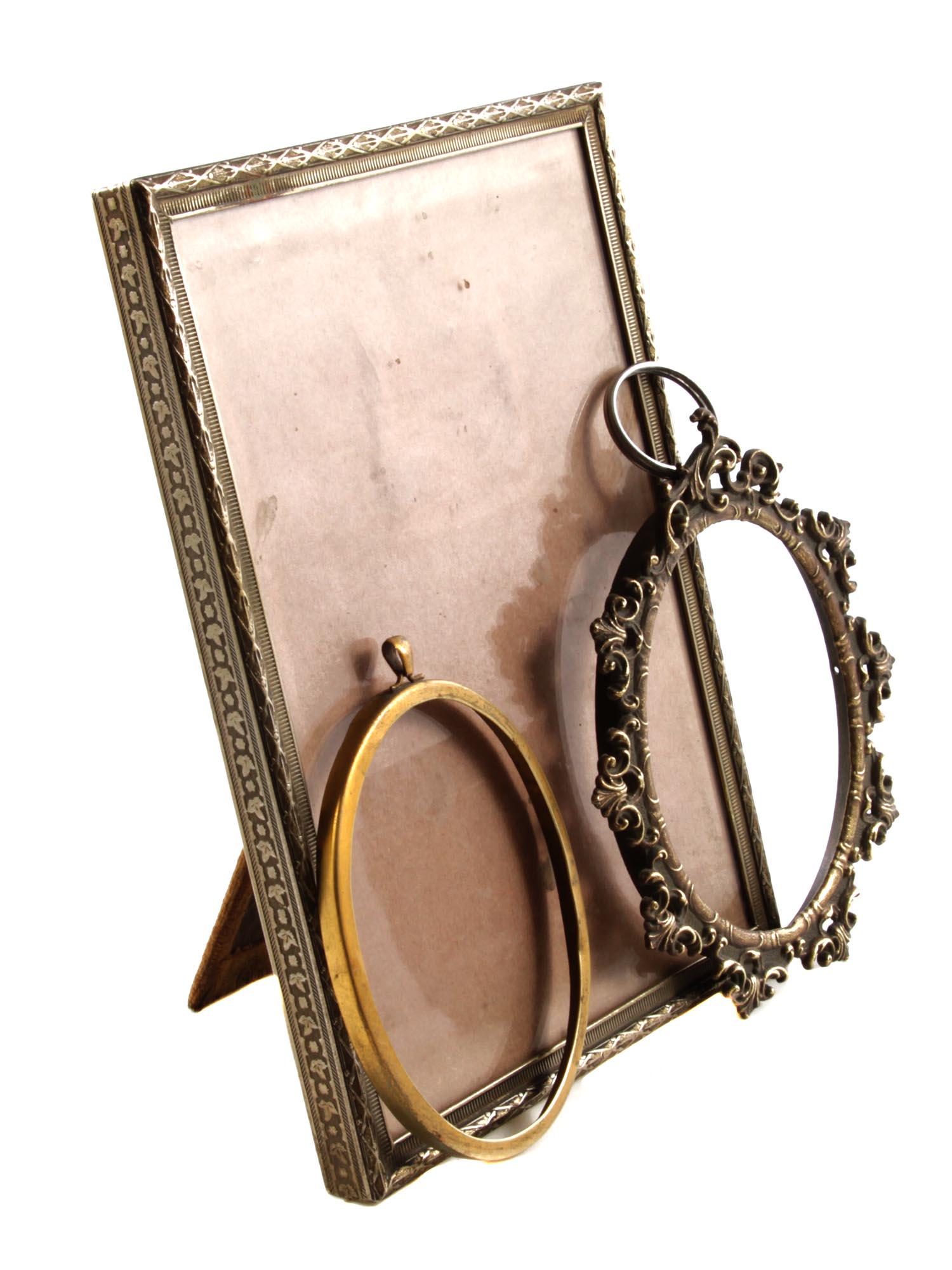 A SET OF THREE ANTIQUE PHOTO FRAMES: The lot includes three photo frames from the late 19th - early 20th century: a large rectangular metal frame with a border decorated with embossed foliage, an oval gold-tone metal frame with a hanging