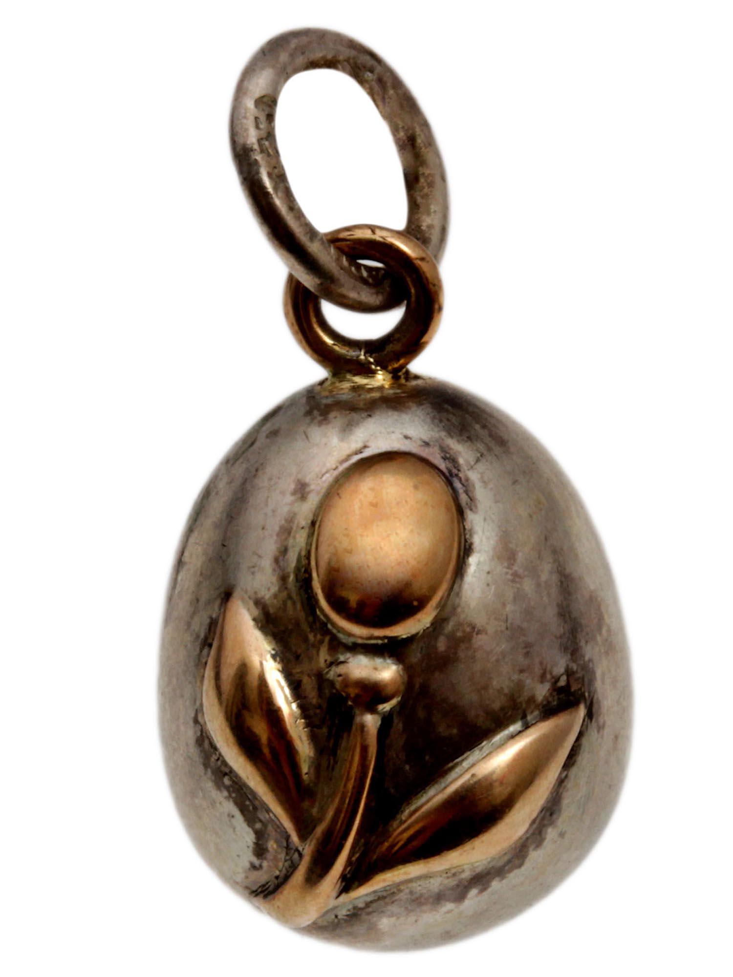 A RUSSIAN SILVER AND GOLD EGG PENDANT: A Russian miniature egg pendant made of silver with an embossed gold flower in the center and a gold ring on top. Hallmarks on the loop: 84 silver Russian standard and master's initials.Weight: 1.6 g.