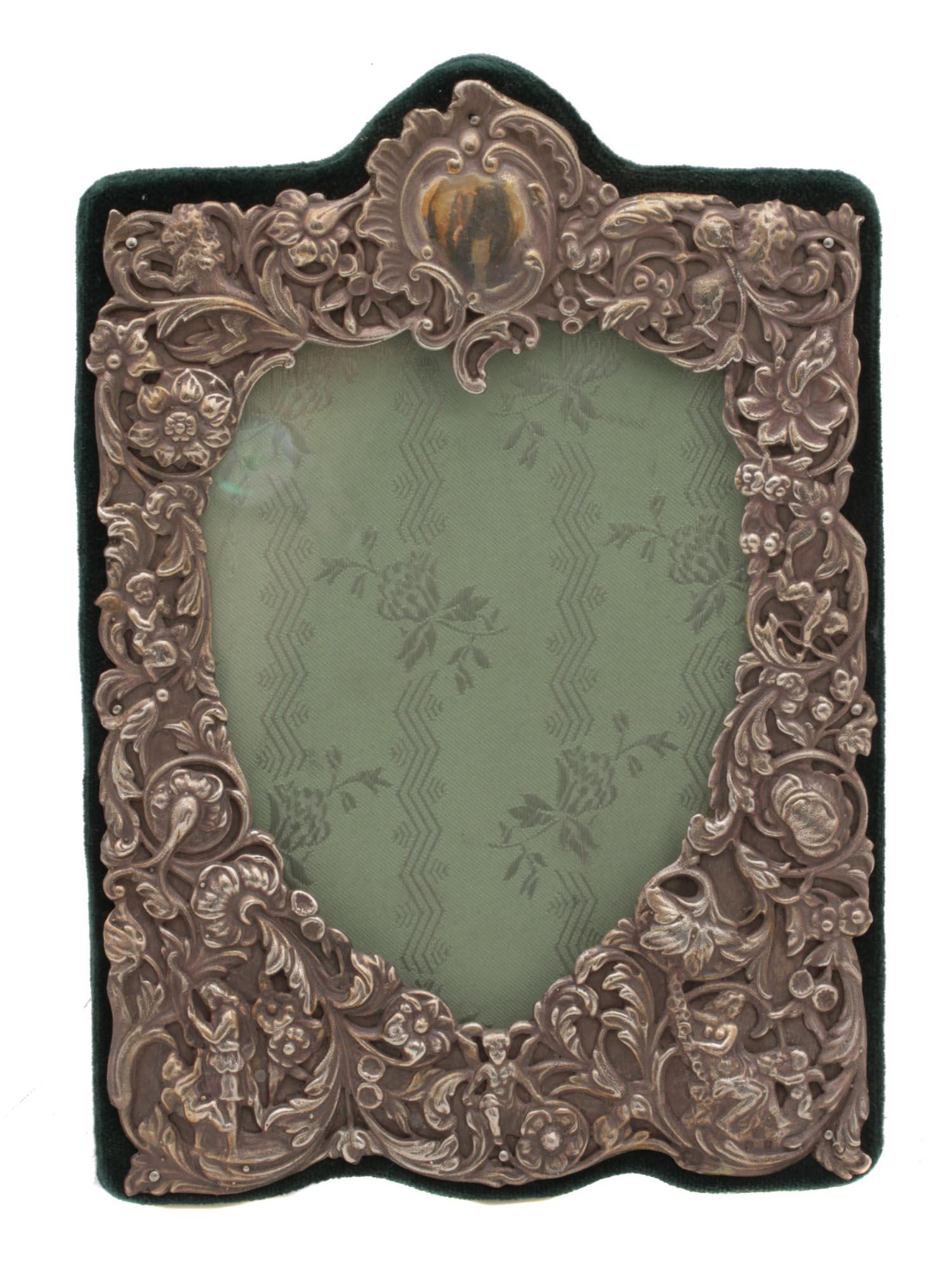 AN ANTIQUE ENGLISH SILVER PHOTO FRAME: A lovely English silver baroque photo frame. The frame is decorated with intricate relief patterns with intertwining flowers, figures of people and animals. The frame is upholstered in dark green velv