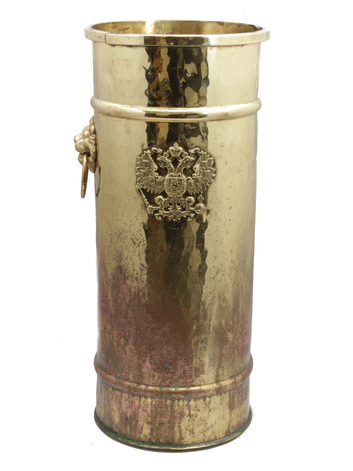 A RUSSIAN BRASS AMPHRA-SHAPED UMBRELLA STAND 19 C: Of a cylindrical form brass hand-hammered umbrella stand featuring a Russian Imperial double-headed eagle cast overlay.Ca. 1890. Dimensions: H: 22 1/4 in.