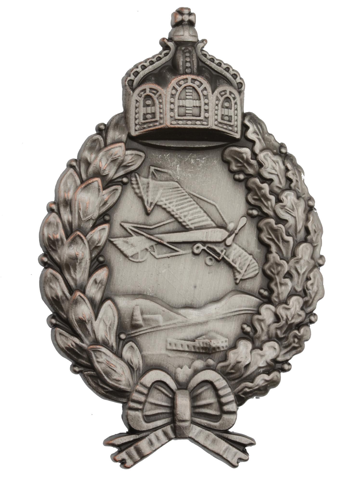 A WWI GERMAN LUFTWAFFE ARMY PILOT BADGE: A WWI German Imperial Luftwaffe Army Pilot commemorative badge pin. The badge made in a wreath shape with a crown and bow and a flying plane in the middle. Marked with hallmarks on the backside. Dimen