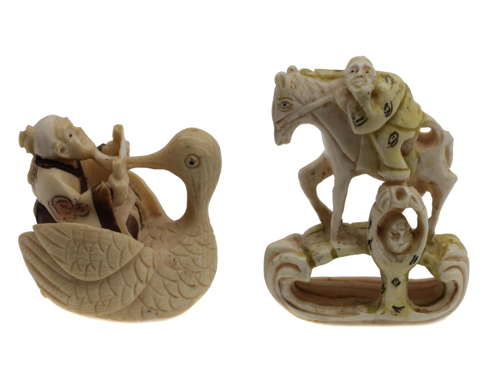 A PAIR OF ANTIQUE JAPANESE CARVED NETSUKE: The lot includes two Japanese early 20th-century netsukes. One netsuke depicts Fukurokuju god on a crane, and the other netsuke depicts a rider on a bridge and a second figure nearby. Perhaps these ar