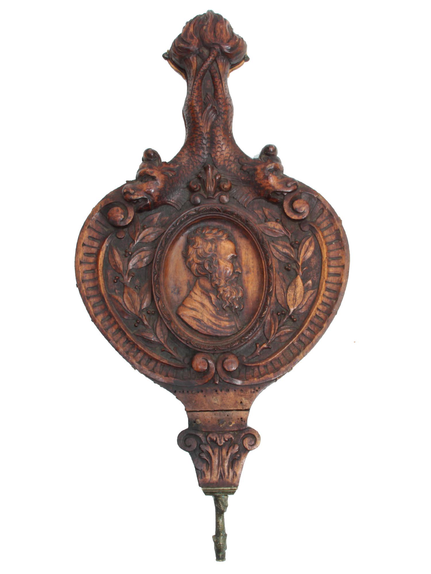 A LATE 18TH CENTURY CARVD WOOD FIREPLACE BELLOWS: A fine wooden carved in high relief Victorian Era fireplace bellows depicting a profile of a man in the Renaissance style. The handle is carved as two mythological dragon tails, the back features two 