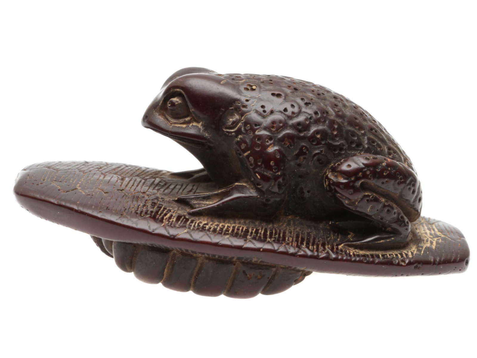 AN ANTIQUE JAPANESE CARVED WOOD NETSUKE OF A TOAD: Original antique Japanese netsuke hand-carved from dark wood. Depicts a toad sitting on a straw sandal. Circa: the late 19th to early 20th century. Dimensions: L: 2 1/4 in.