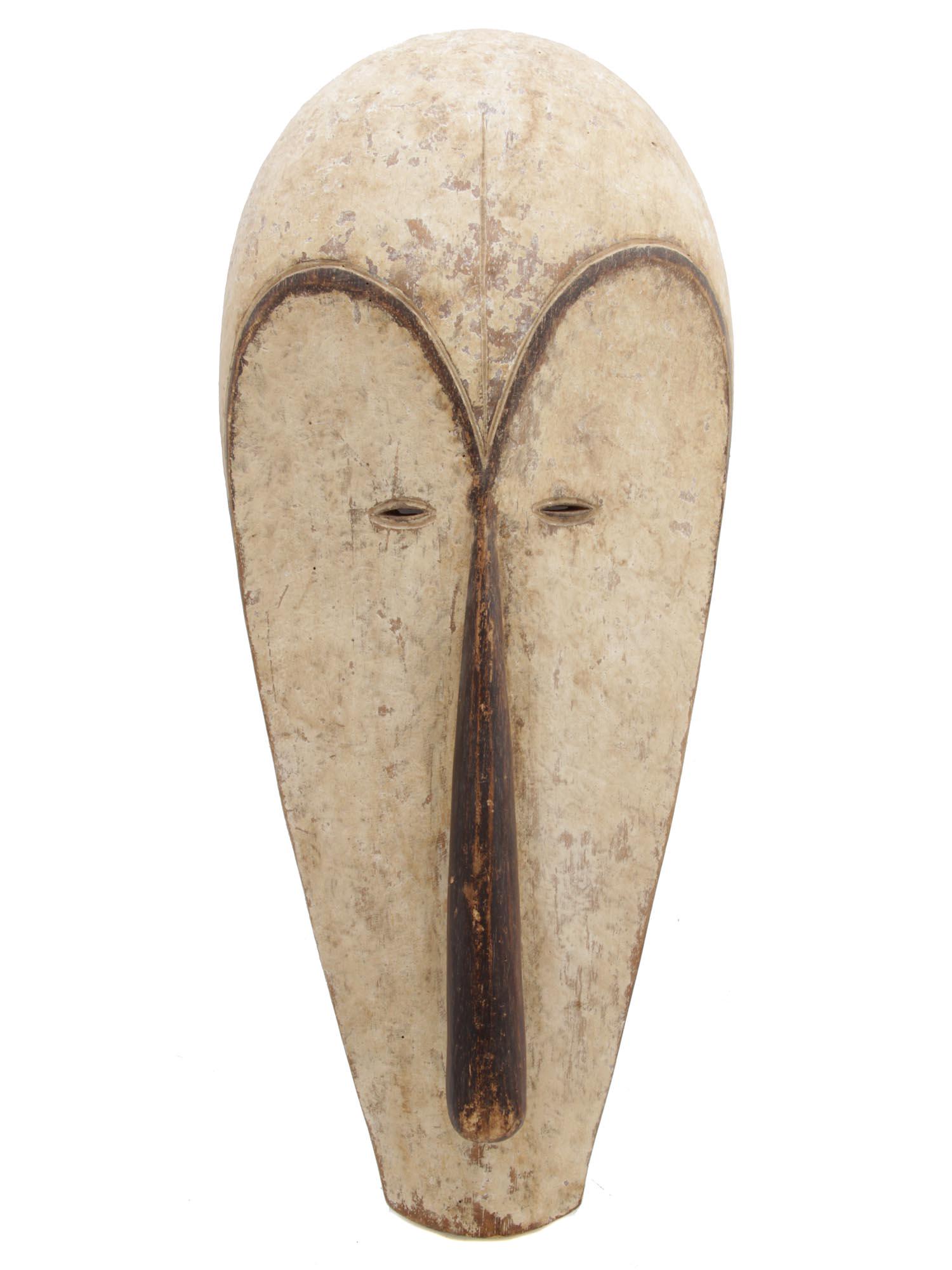 AN ANTIQUE AFRICAN NGIL MASK, GABON: Early 20th-century stylized Ngil face mask. Fang Tribe, Gabon. Such masks were worn at nightly initiation ceremonies or to punish witches and criminals. The mask is made of wood, covered with white pi