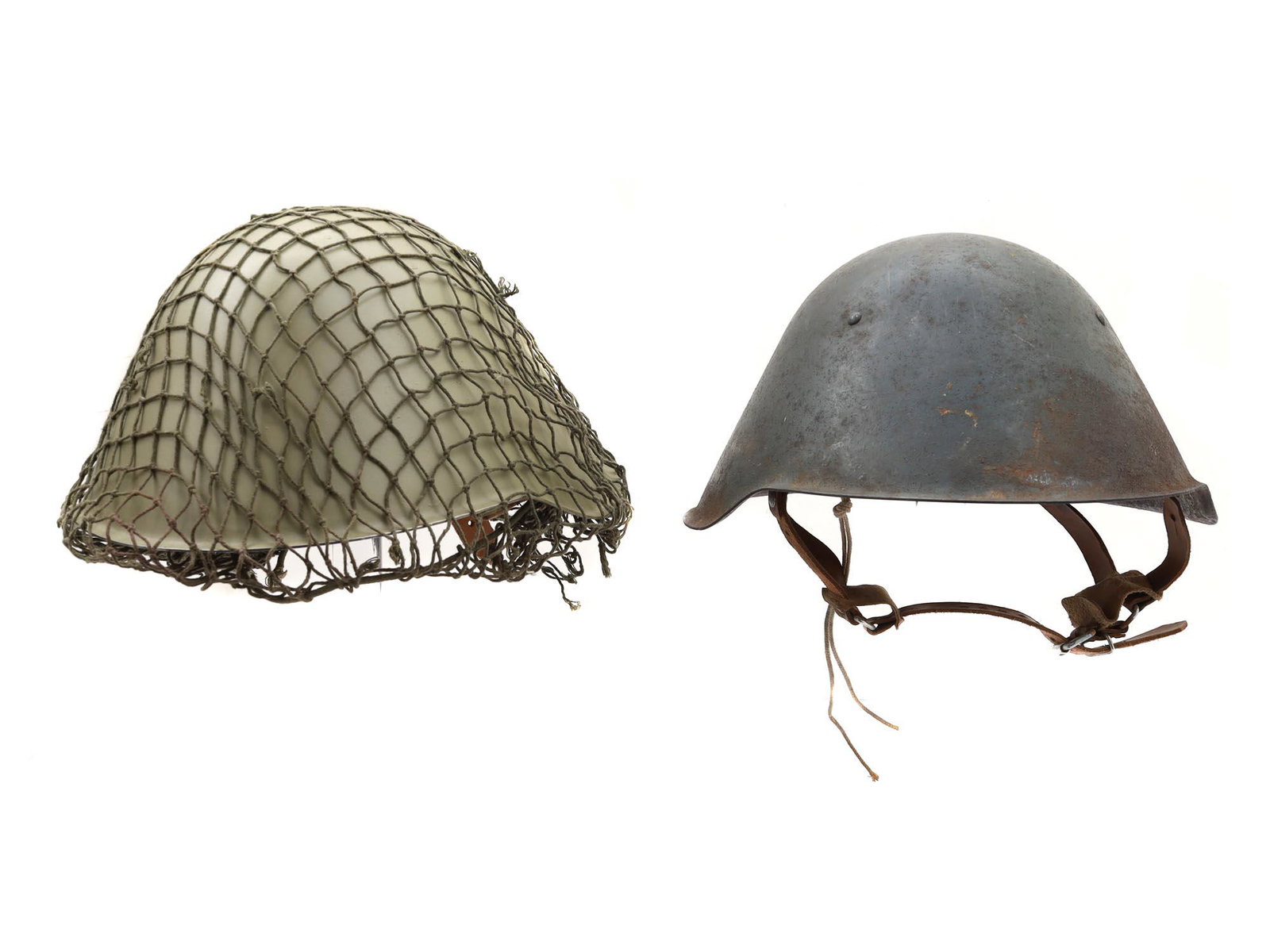 AN EAST GERMAN DDR COMBAT HELMETS, M1956-76: A pair of original Cold War East German M56/76 steel combat helmets, complete with original support frame, leather and chin strap, one helmet has an original camo net. Dimensions: N/A