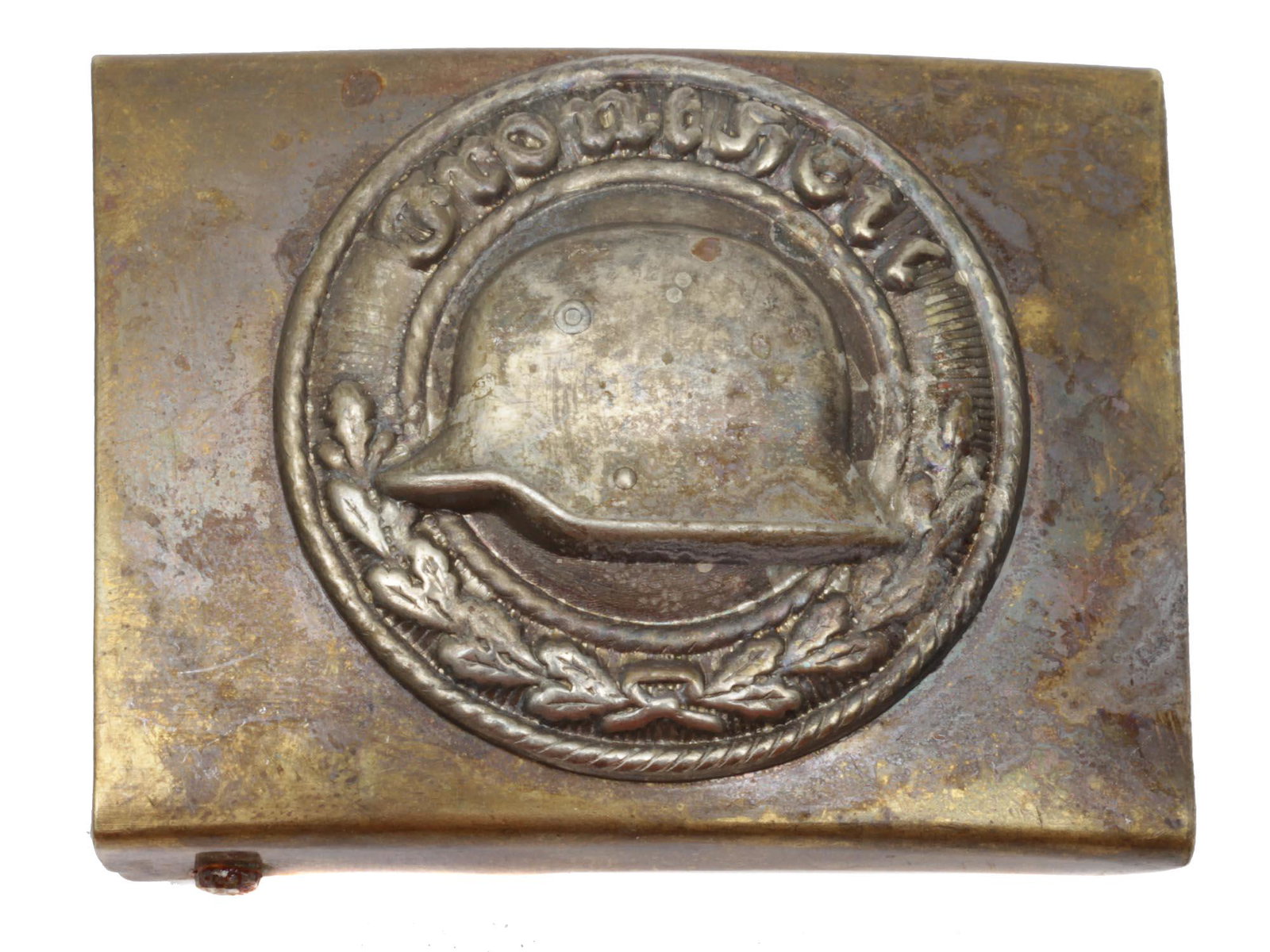 A WWII NAZI GERMAN STAHLHELM BELT BUCKLE VETERANS: A WWII Nazi German Stahlhelm belt buckle for veterans. The front is embossed with a round oak leaf wreath and inscription, Front Heil, encompassing a slightly domed inner field with a steel helmet. In